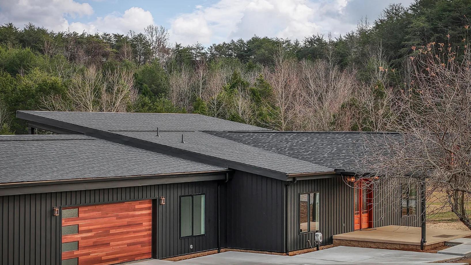 Outside drone view of beautifful black themed modern home with maple wood accents