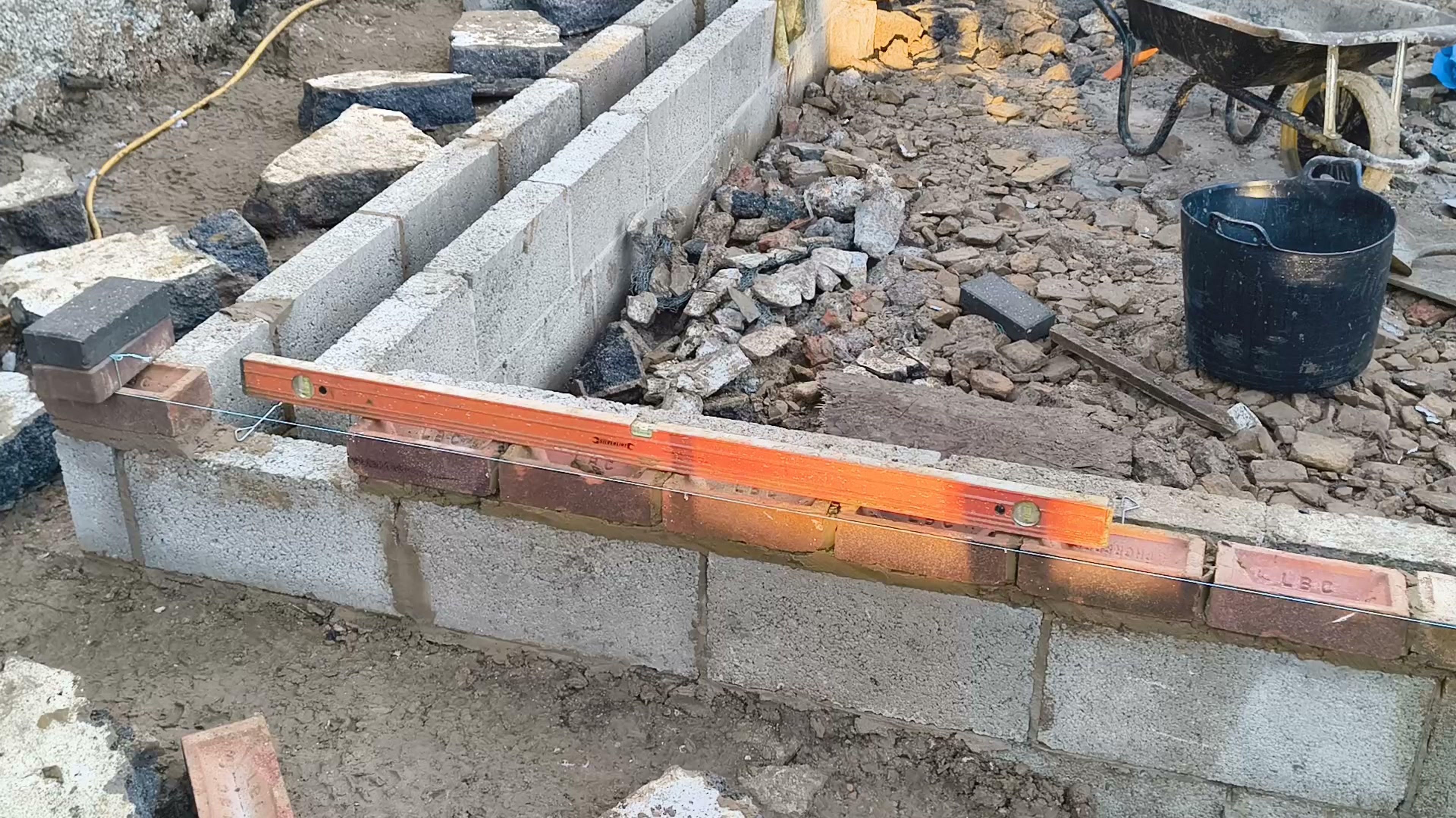 Spirit level on a new brick course above the blockwork for a rear extension in Chigwell