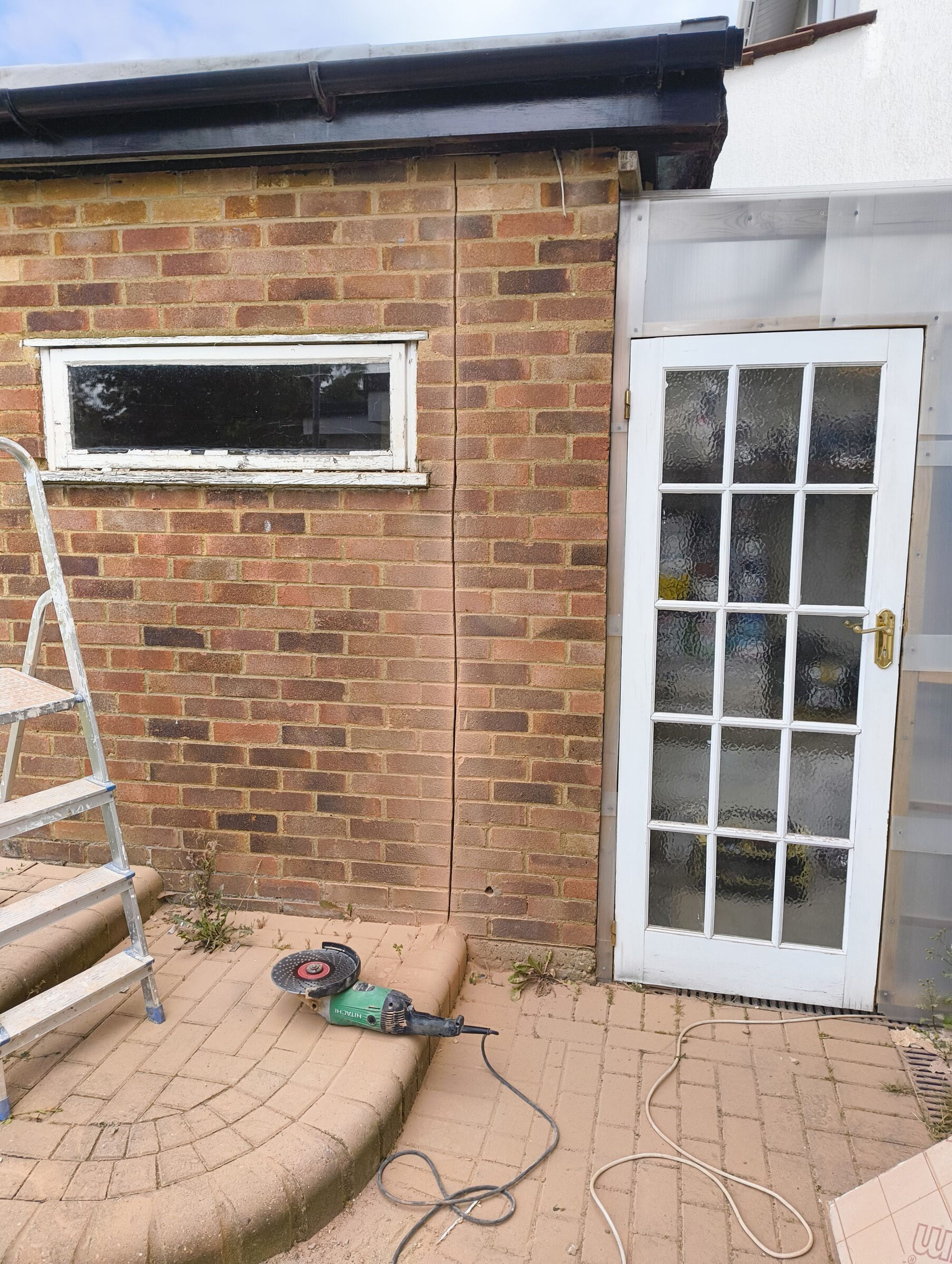 Stepladder set against the brick extension wall in Chigwell, before the opening was cut through.