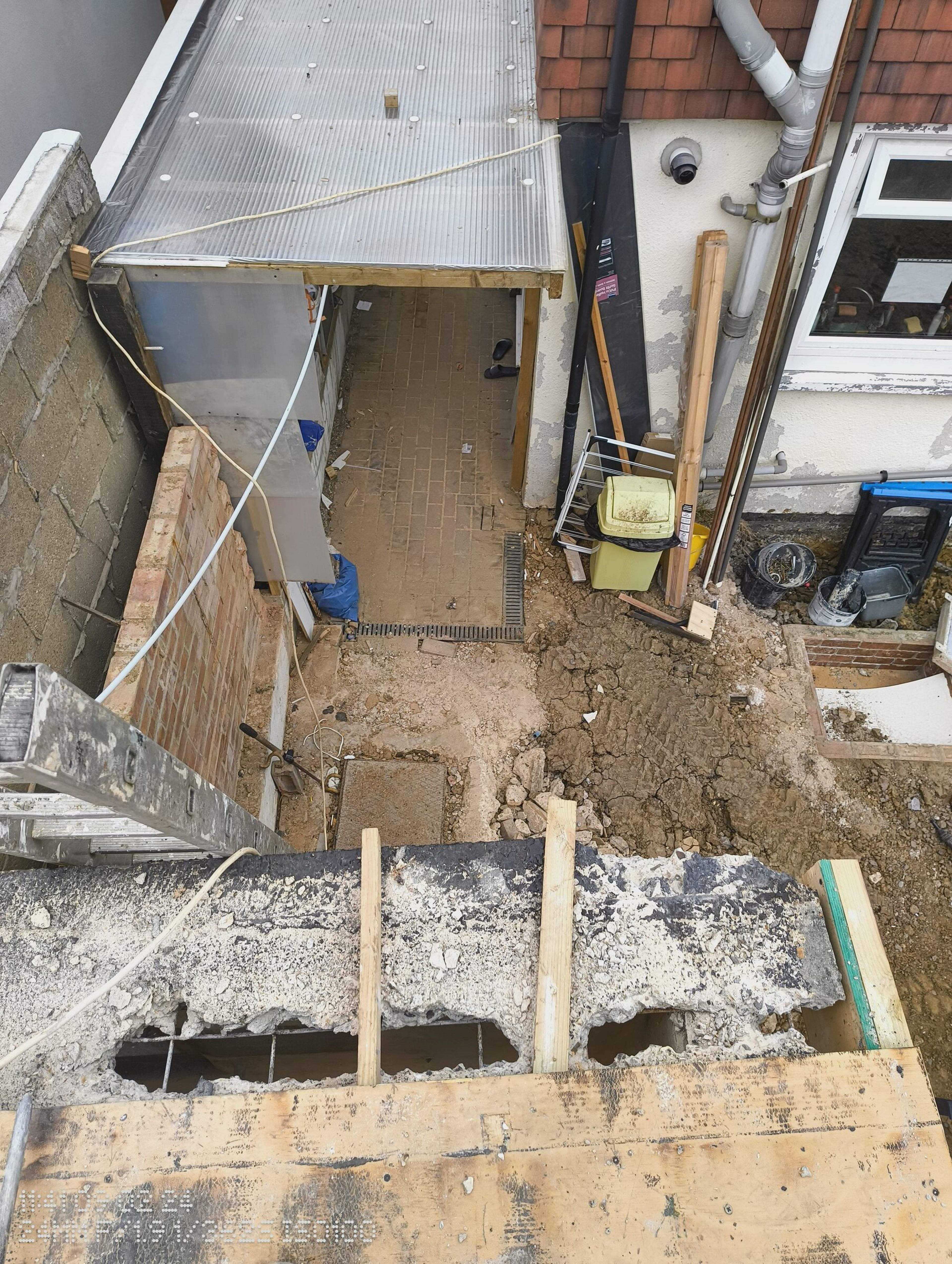 Looking down from the broken roof edge into the side passage and the dug garden beside the house.