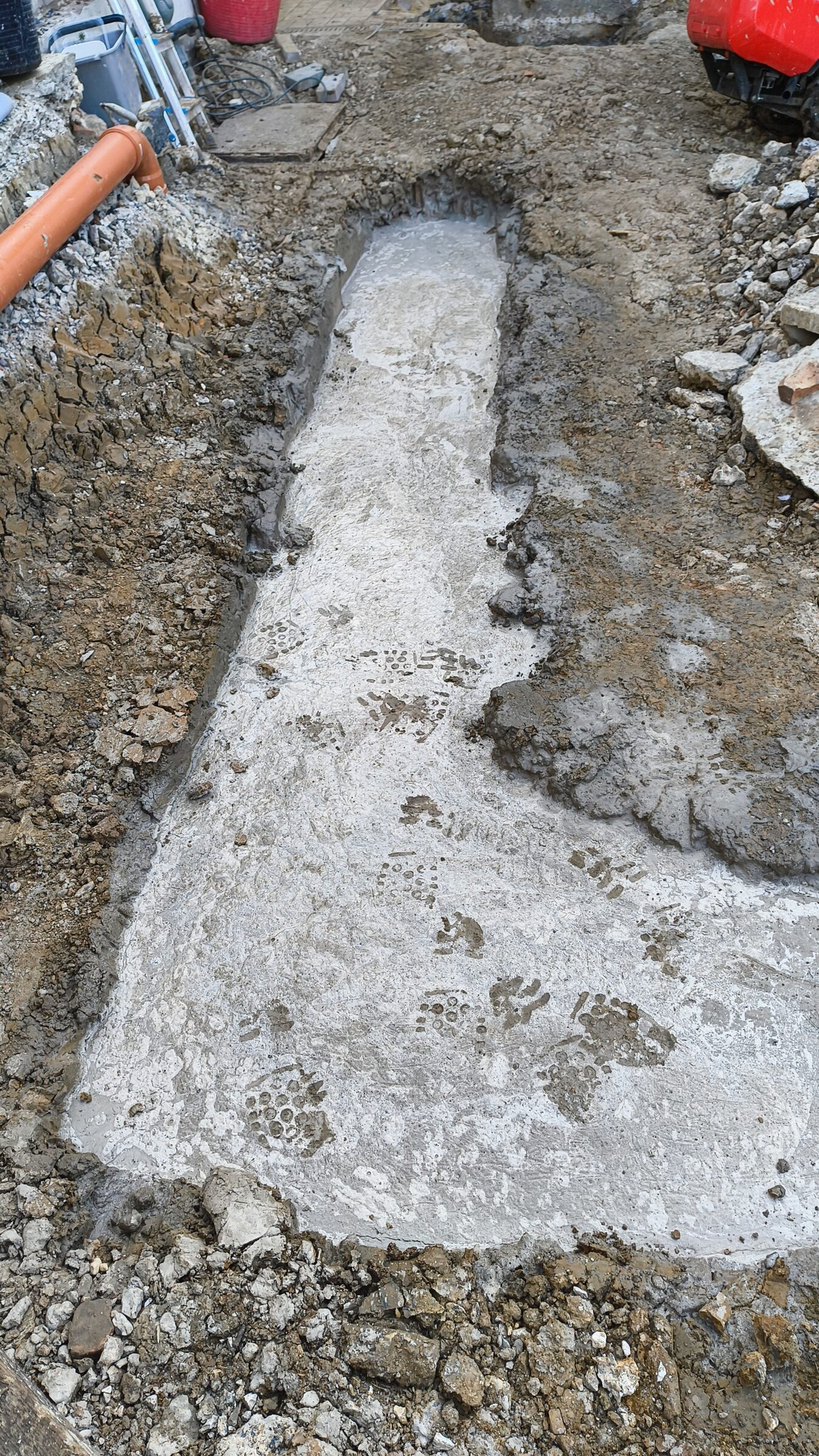 Fresh concrete in a foundation trench for a rear extension in Chigwell, with boot prints across the surface.