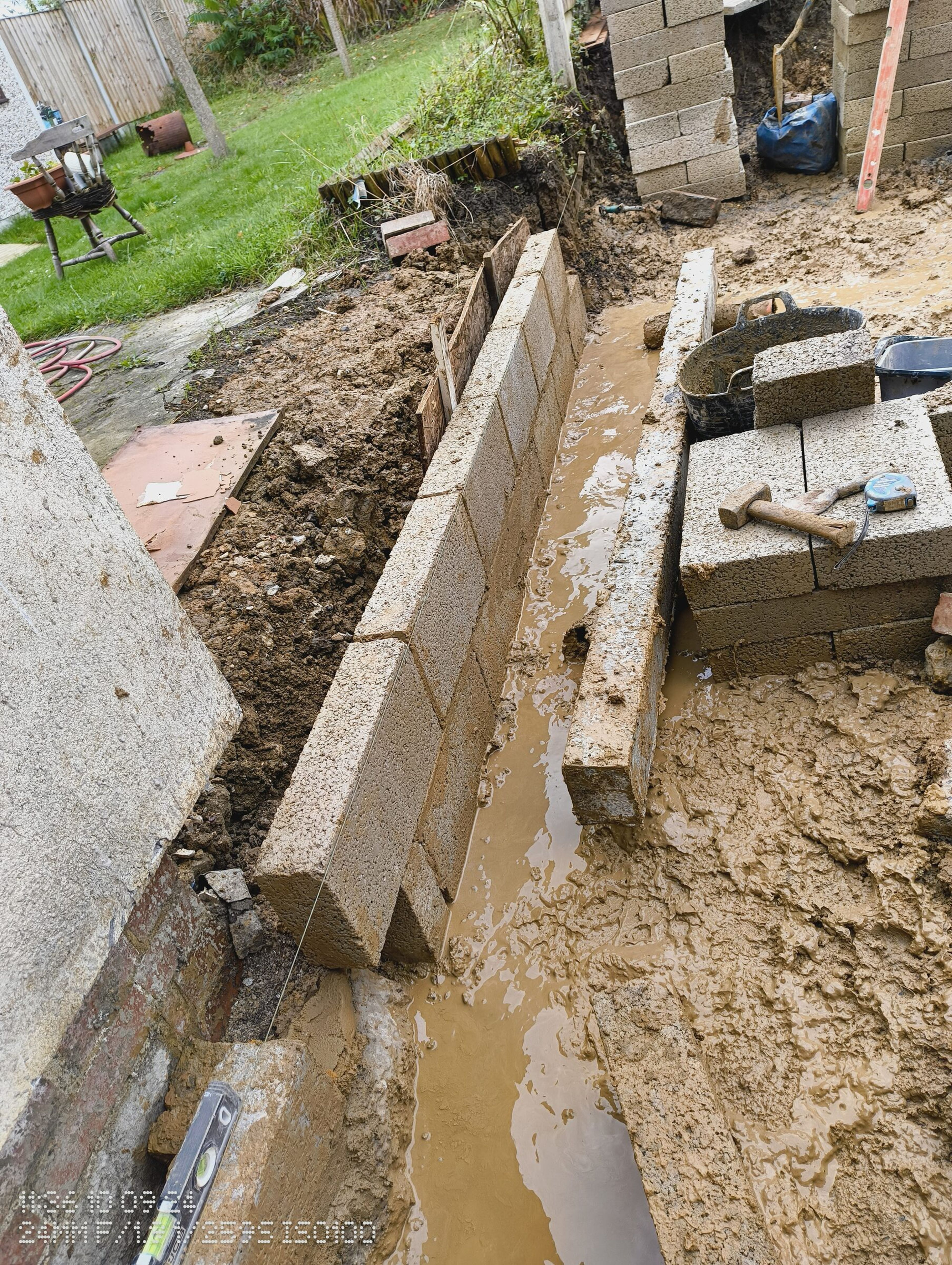 New block wall running beside the house, with the garden and the rest of the site beyond.