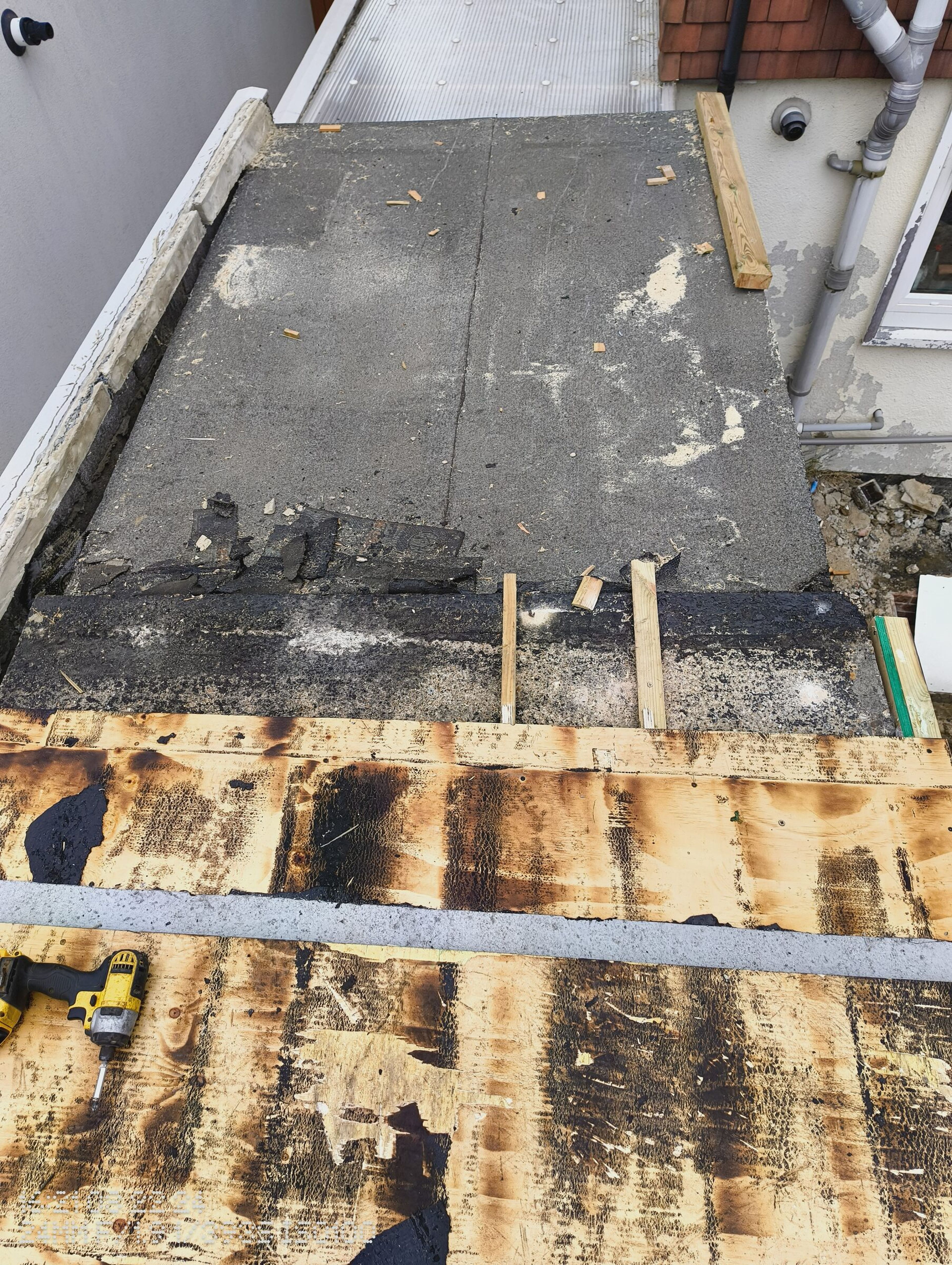 Concrete roof slab exposed behind the stripped timber deck on the rear extension.