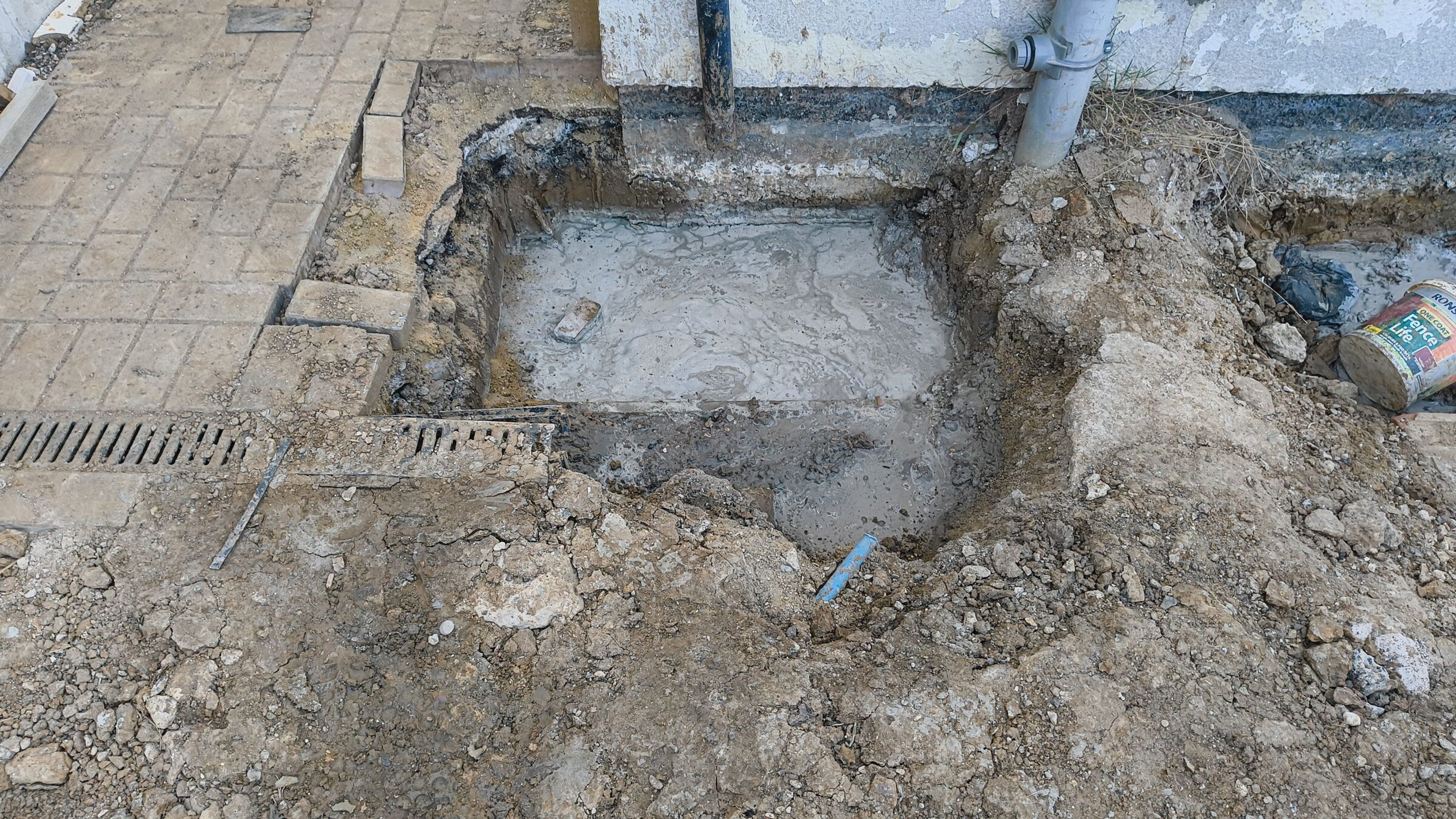 Concrete poured in a foundation pit beside the house wall and patio for a rear extension in Chigwell.