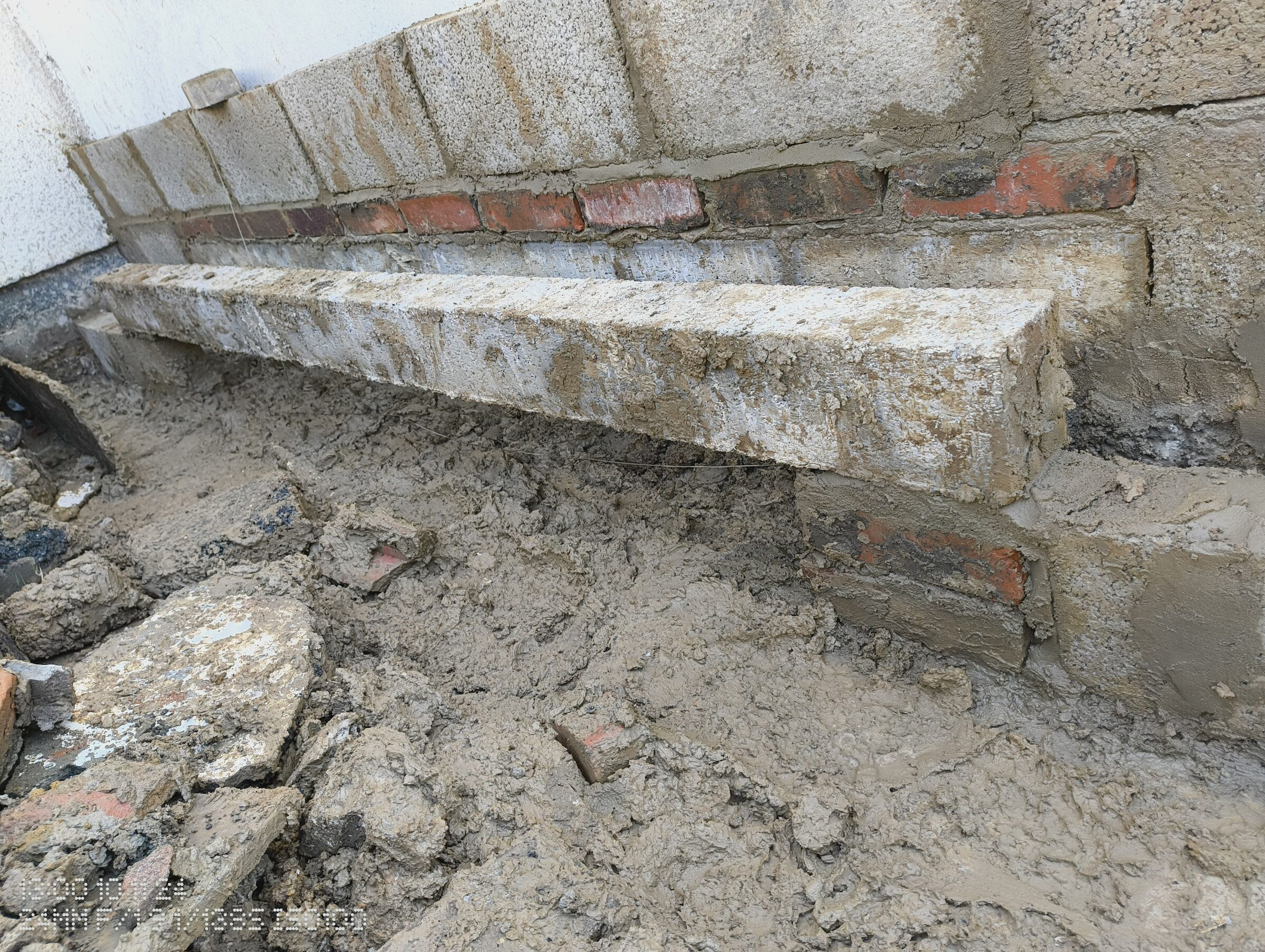 Block and brick courses along the house, with the open trench still in front.