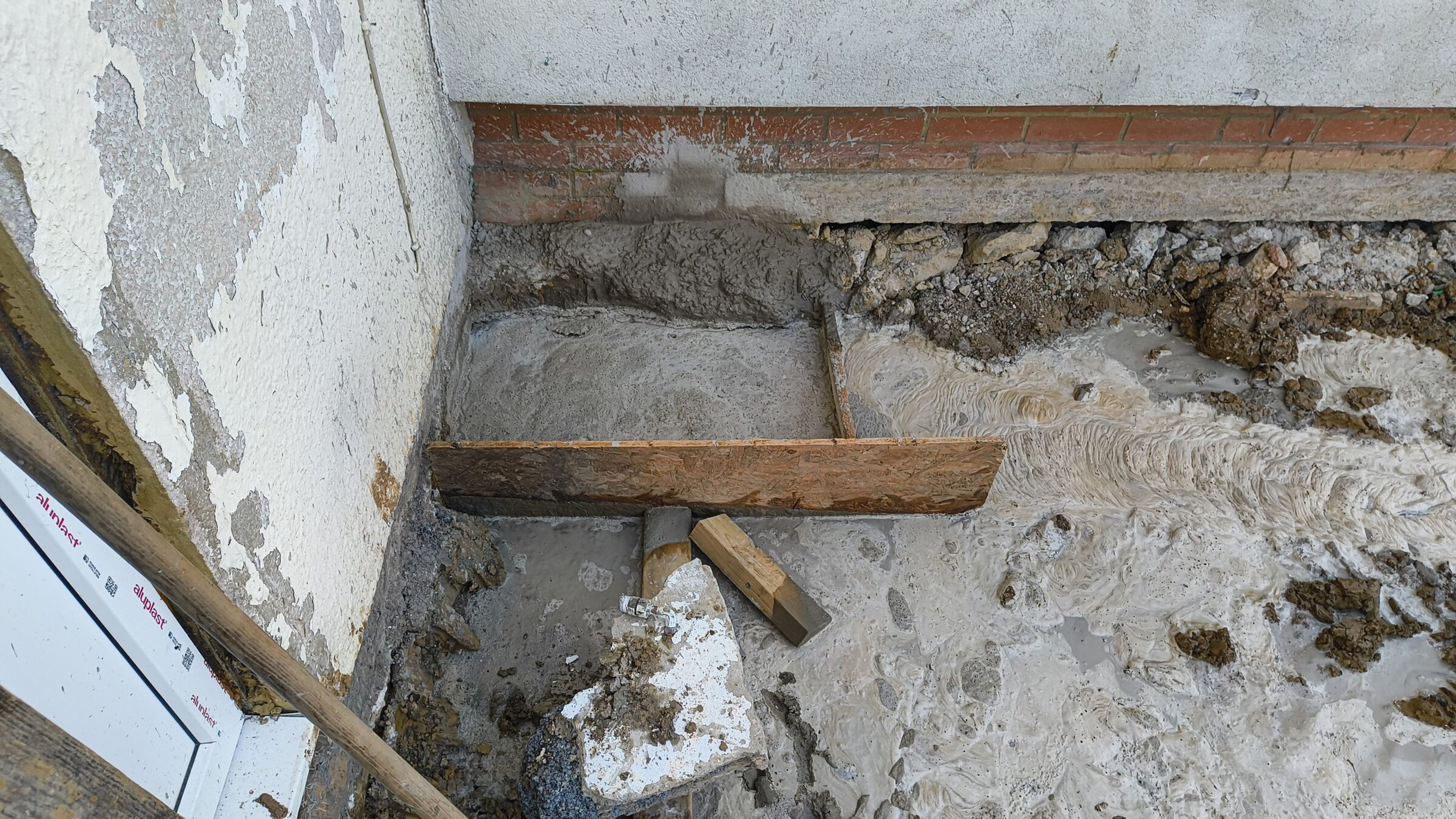 Concrete foundation poured against the existing house wall for a rear extension in Chigwell, with timber set in the pour.