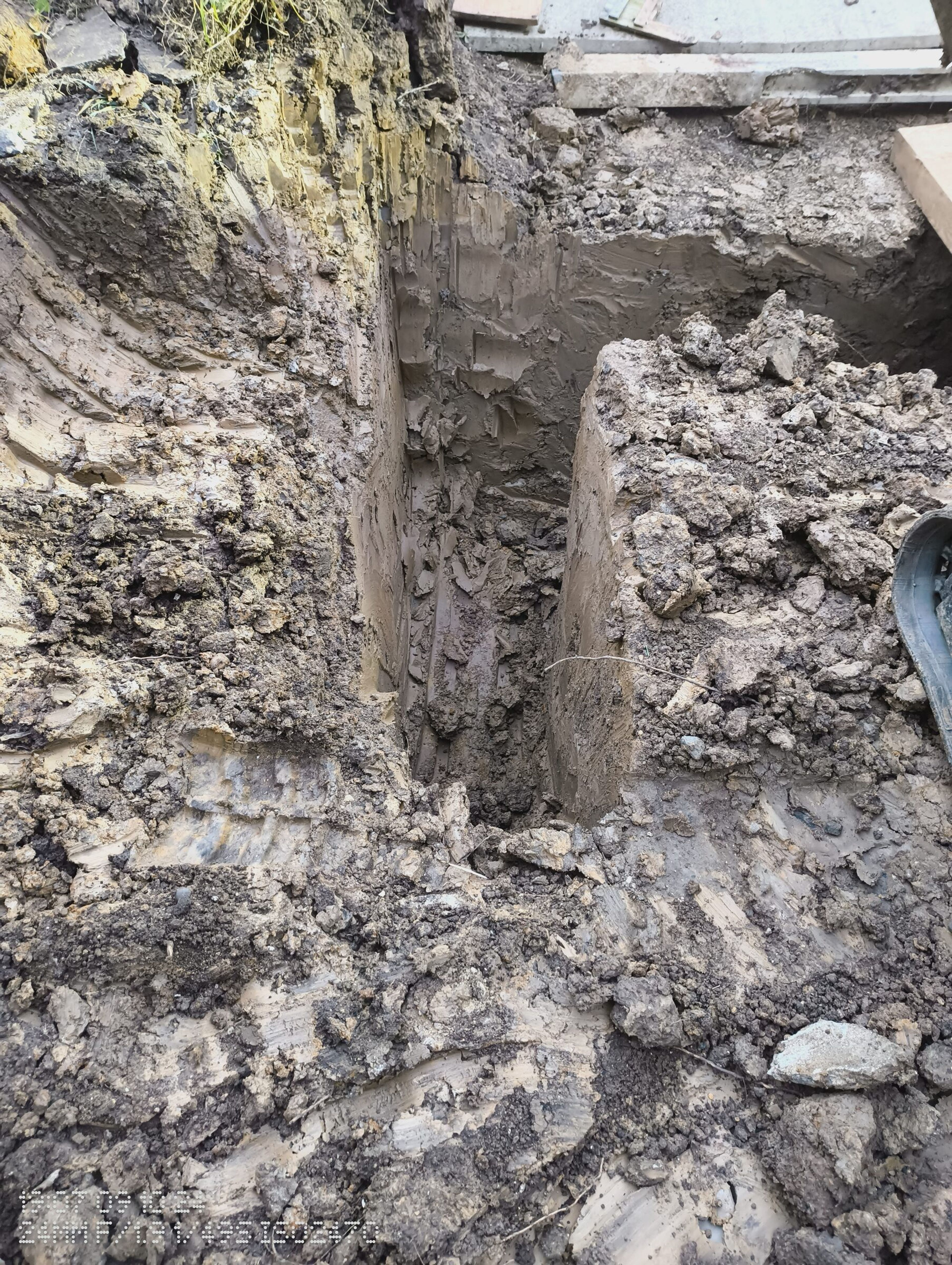 Deep, narrow foundation trench cut into clay soil for a rear extension in Chigwell.