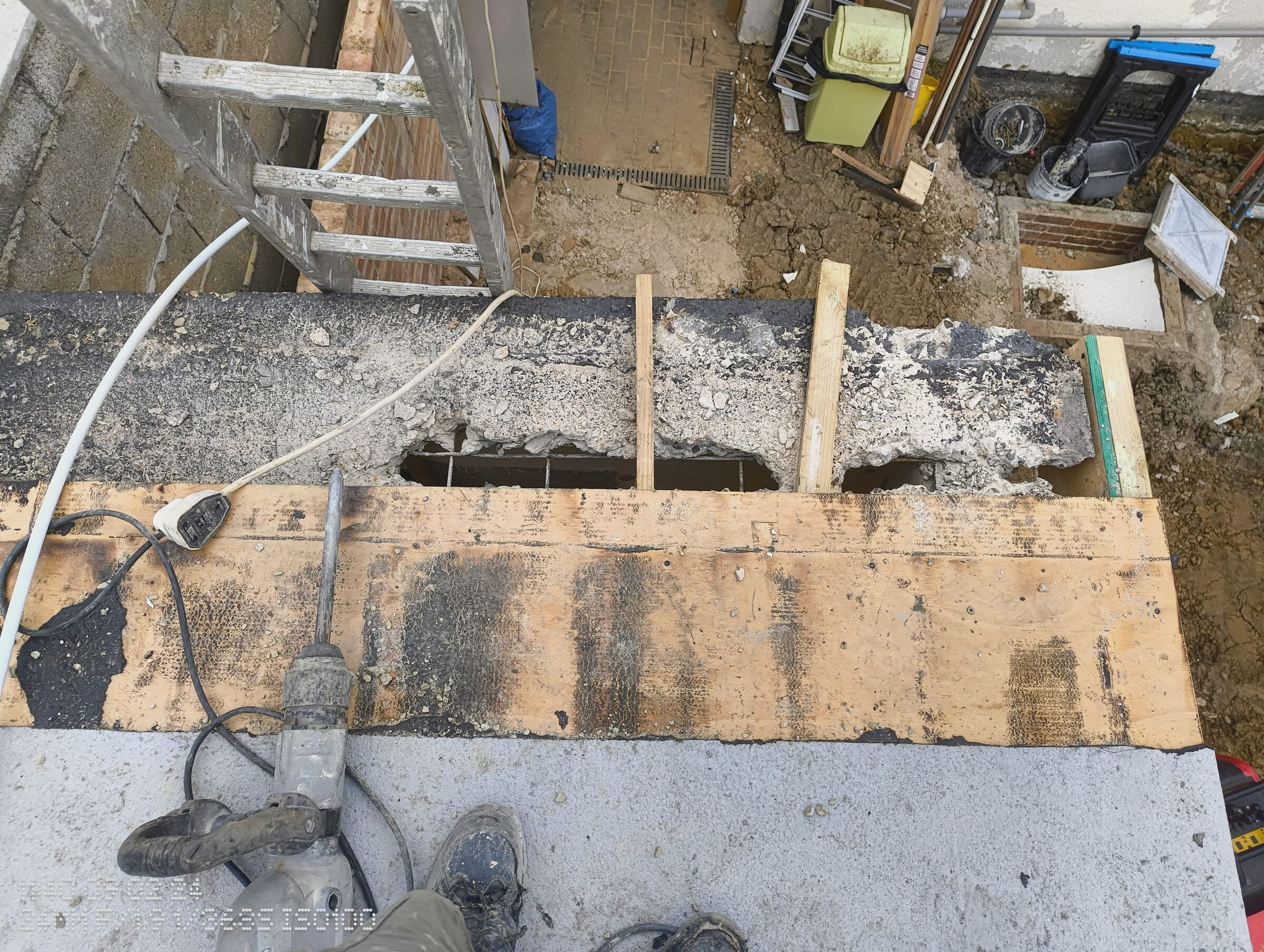 Edge of the concrete roof broken open, with a breaker and timber props over the holes.