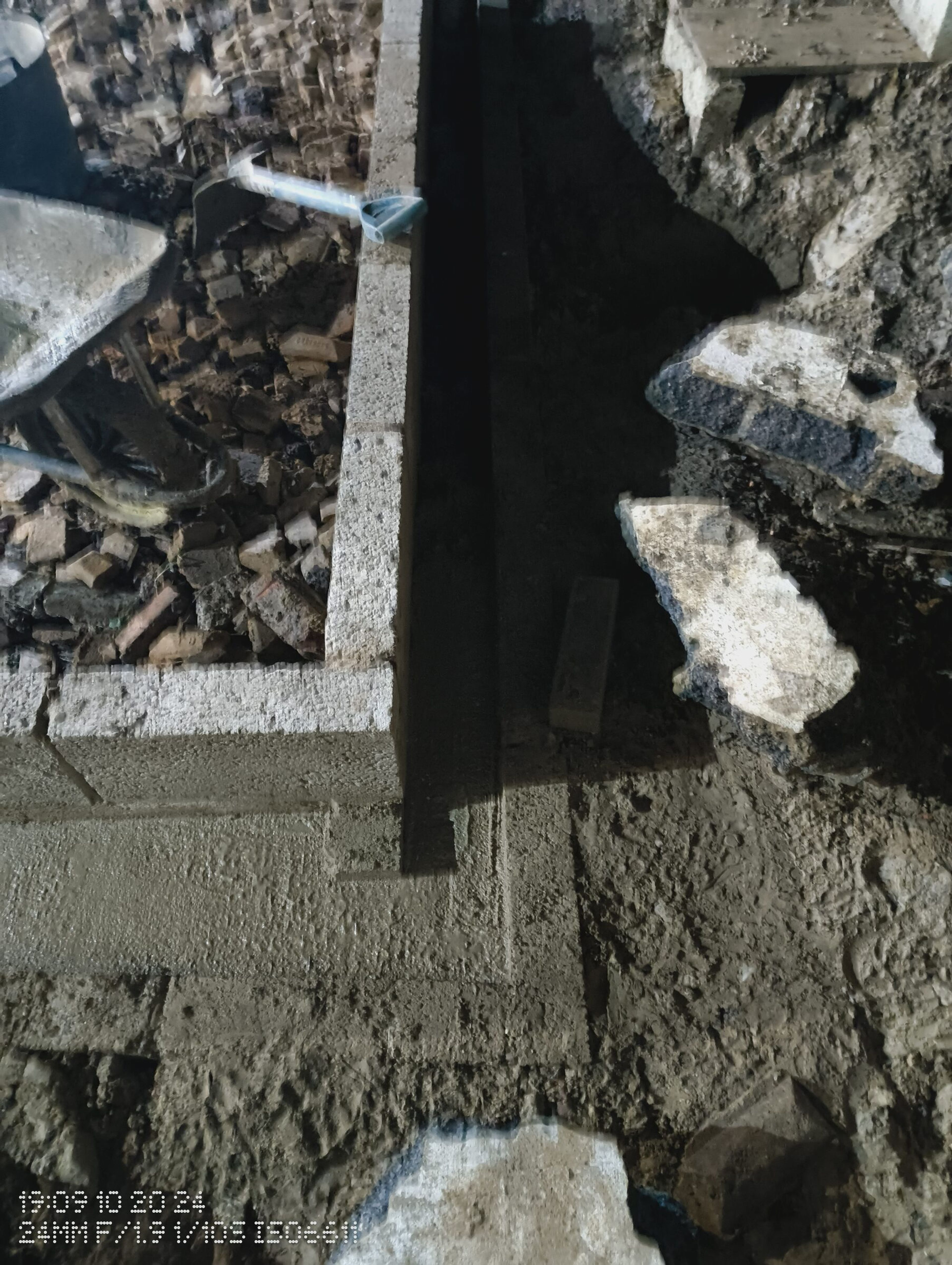 Concrete at the base of the shuttered blockwork, with broken slabs stacked alongside.