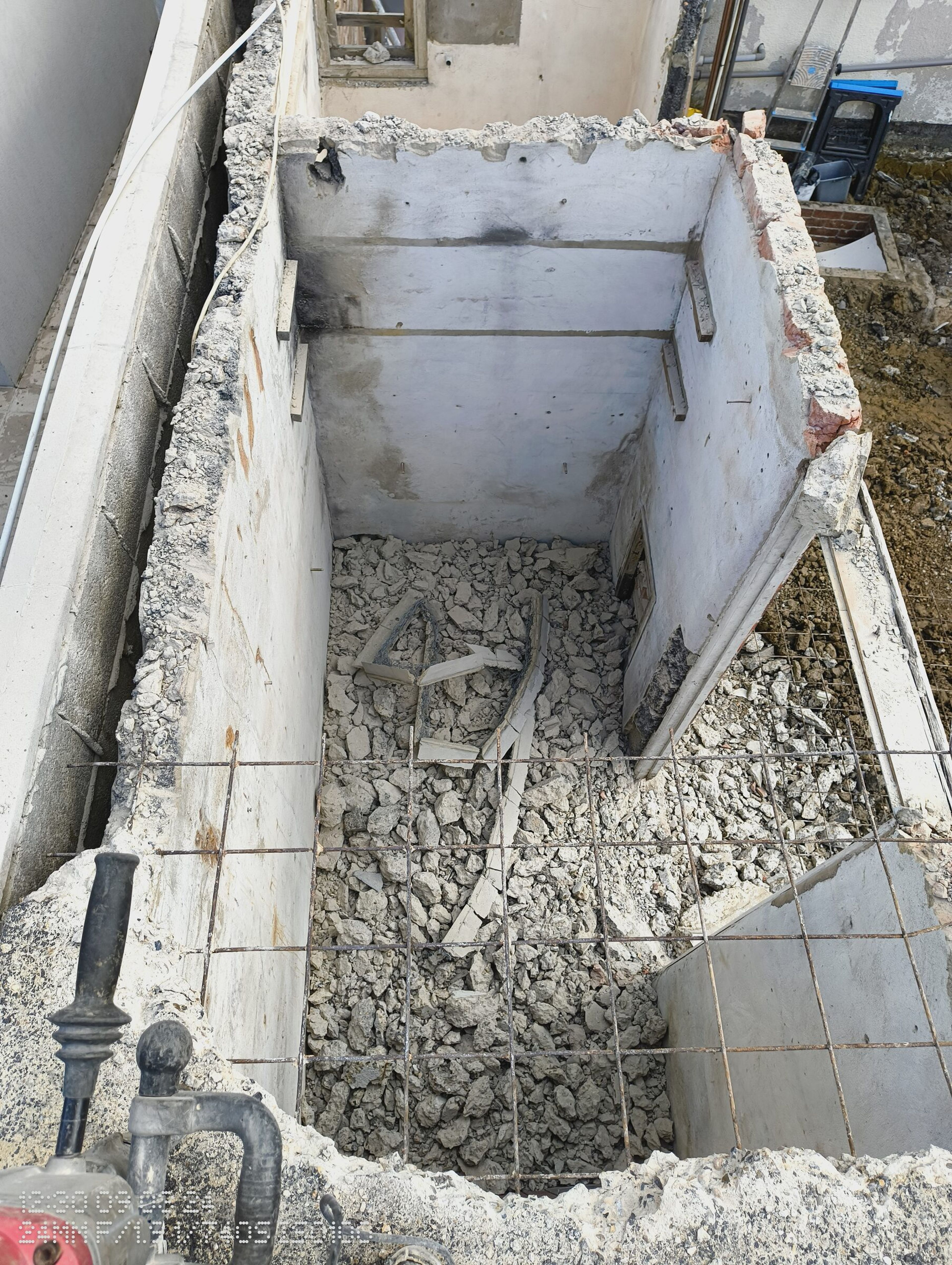 Looking down into the demolished extension, with rubble on the floor and mesh still across the opening.