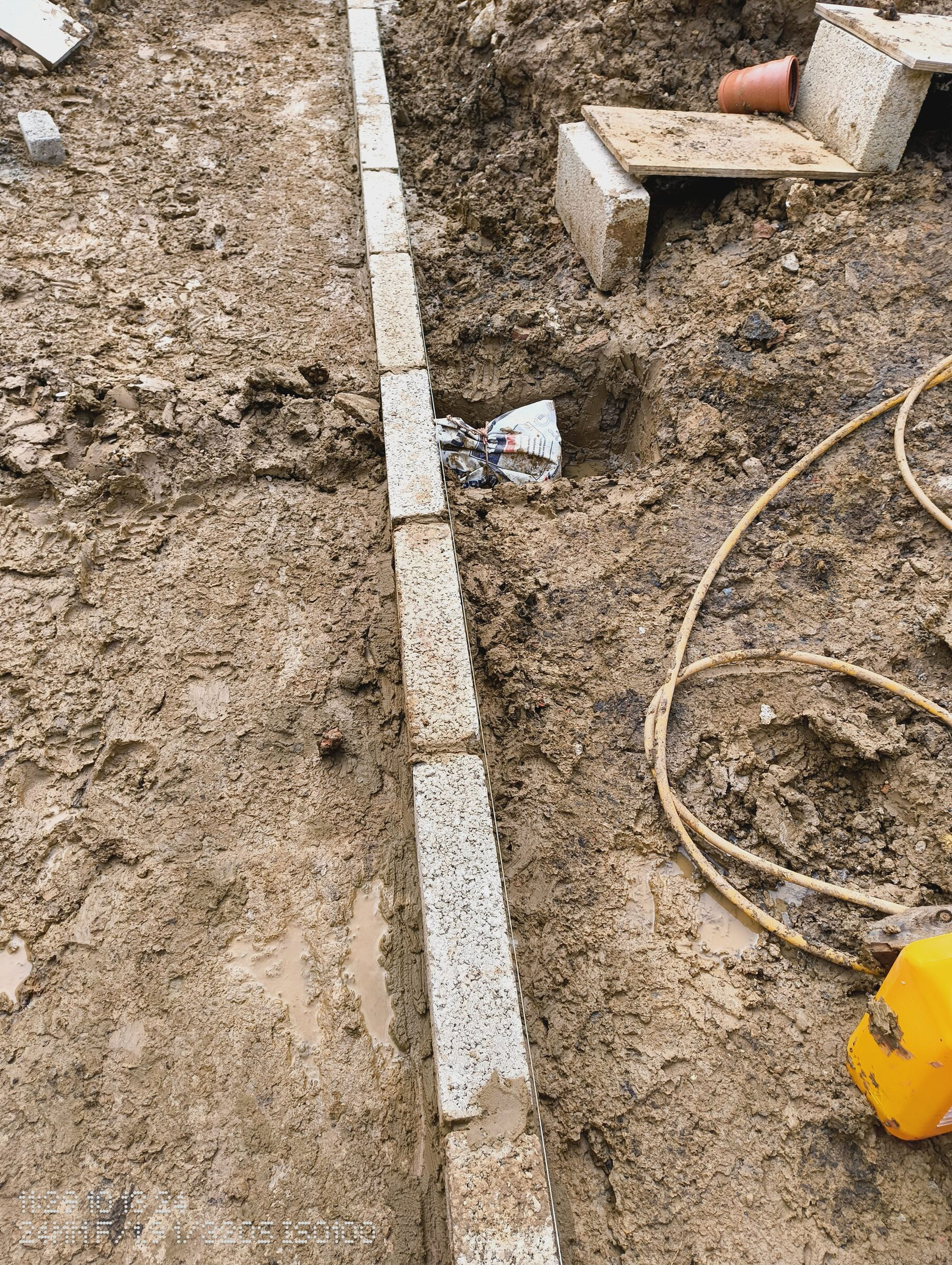 Blockwork along the trench edge, with a hose and a spirit level resting on the blocks.