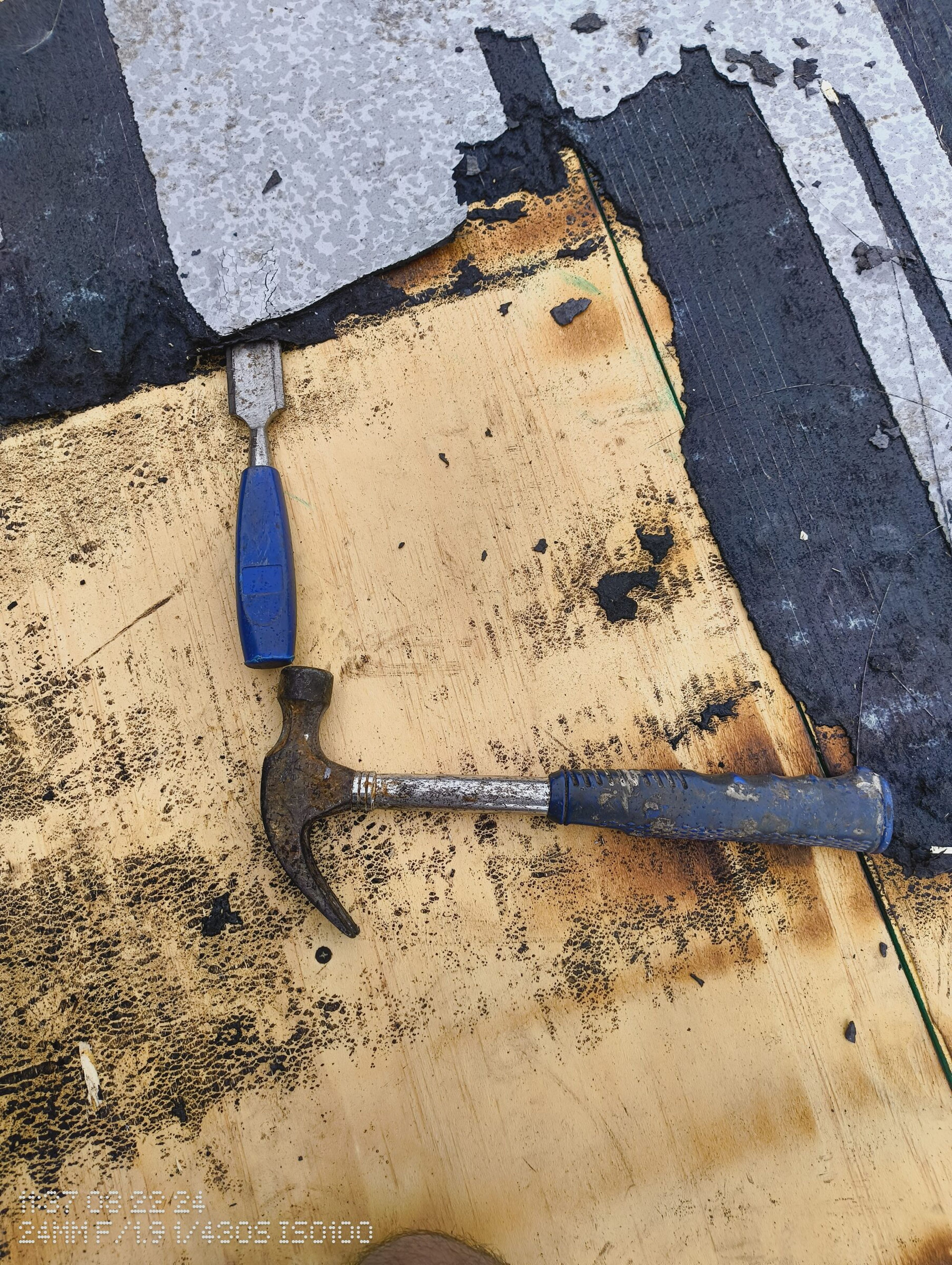 Chisel and hammer on the exposed roof deck where the felt has been cut back.