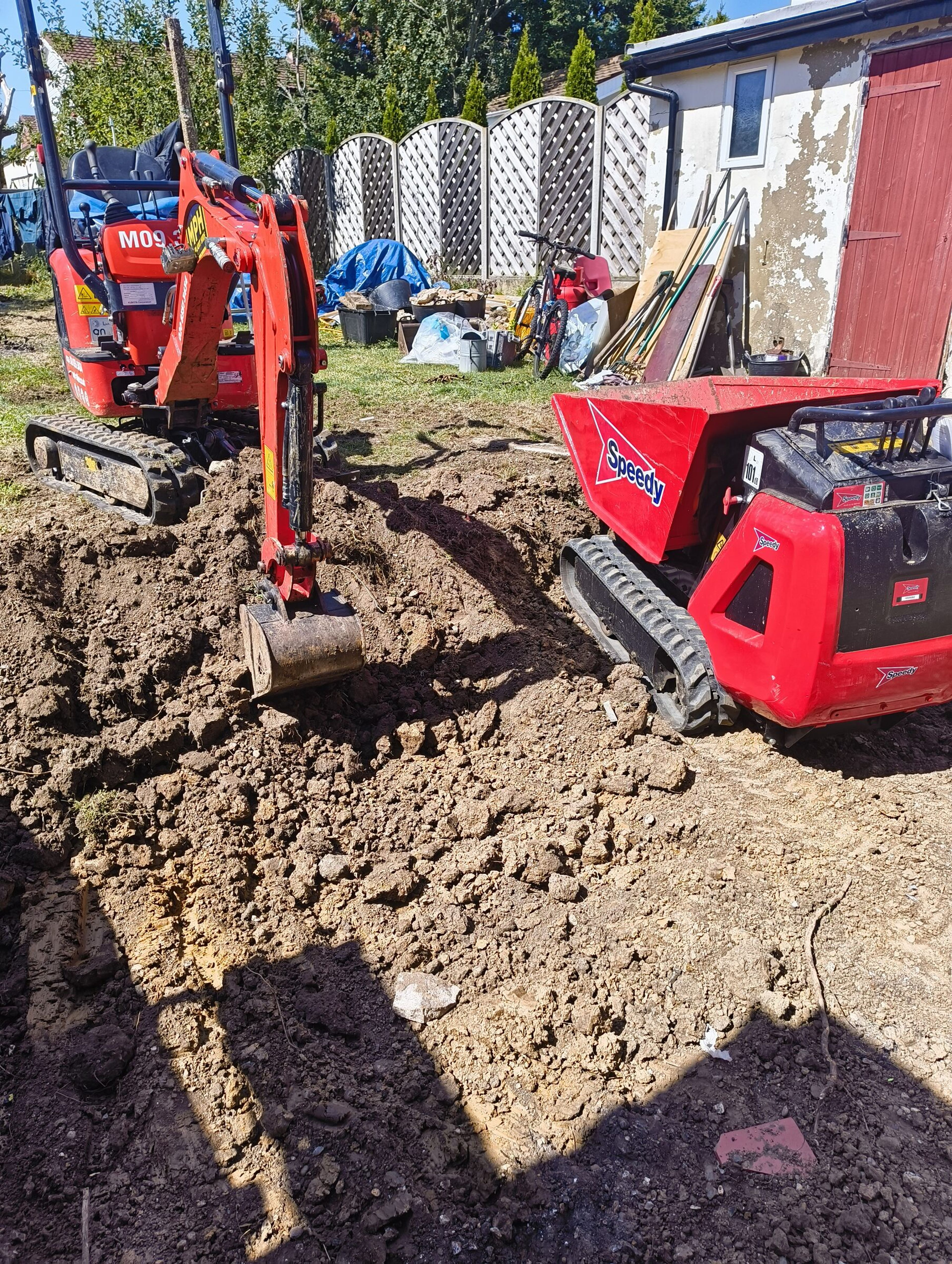 Mini digger clearing spoil and loading a tracked dumper for a Chigwell rear extension.