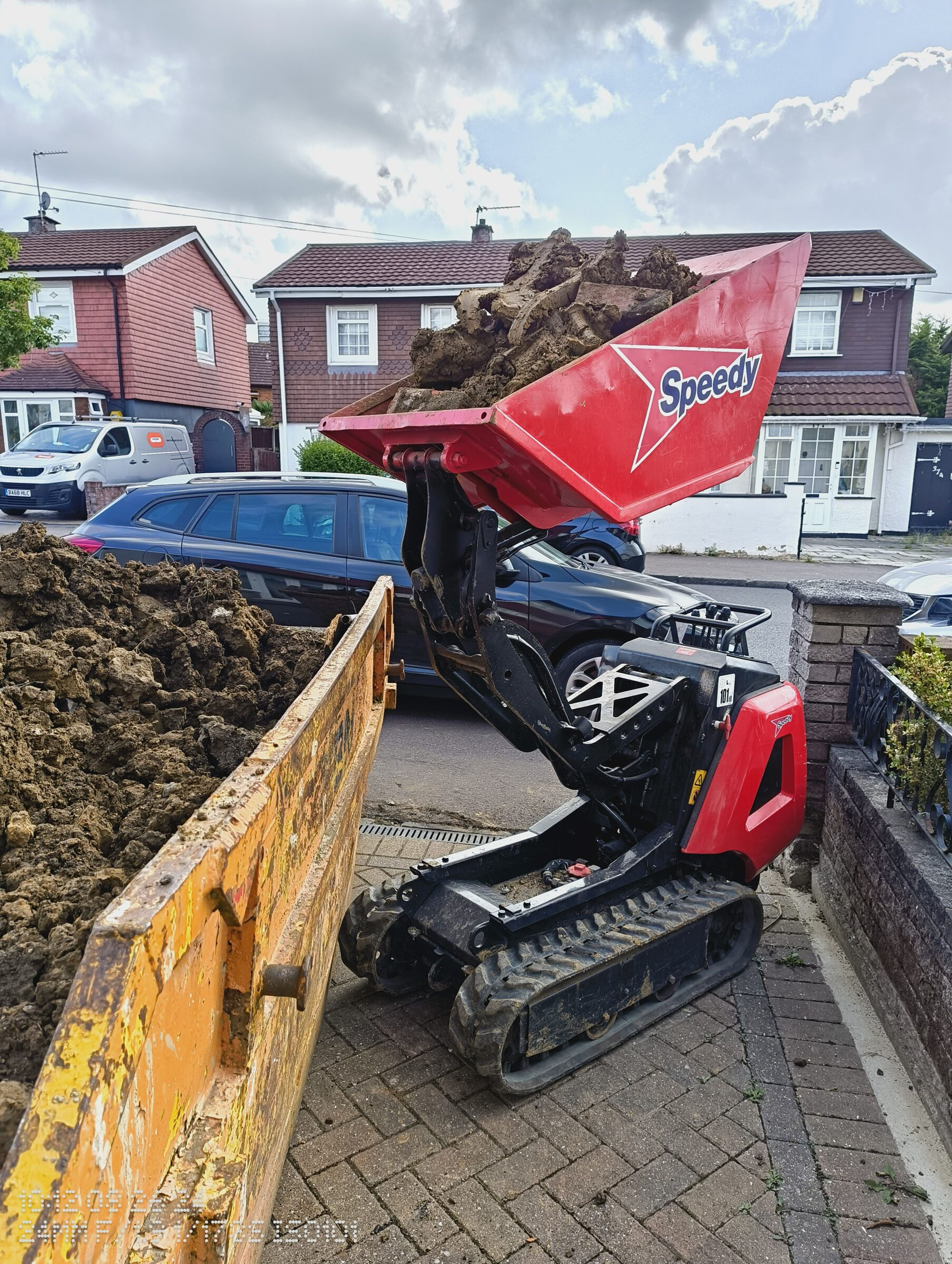Tracked mini dumper tipping soil into a skip for a Chigwell rear extension.