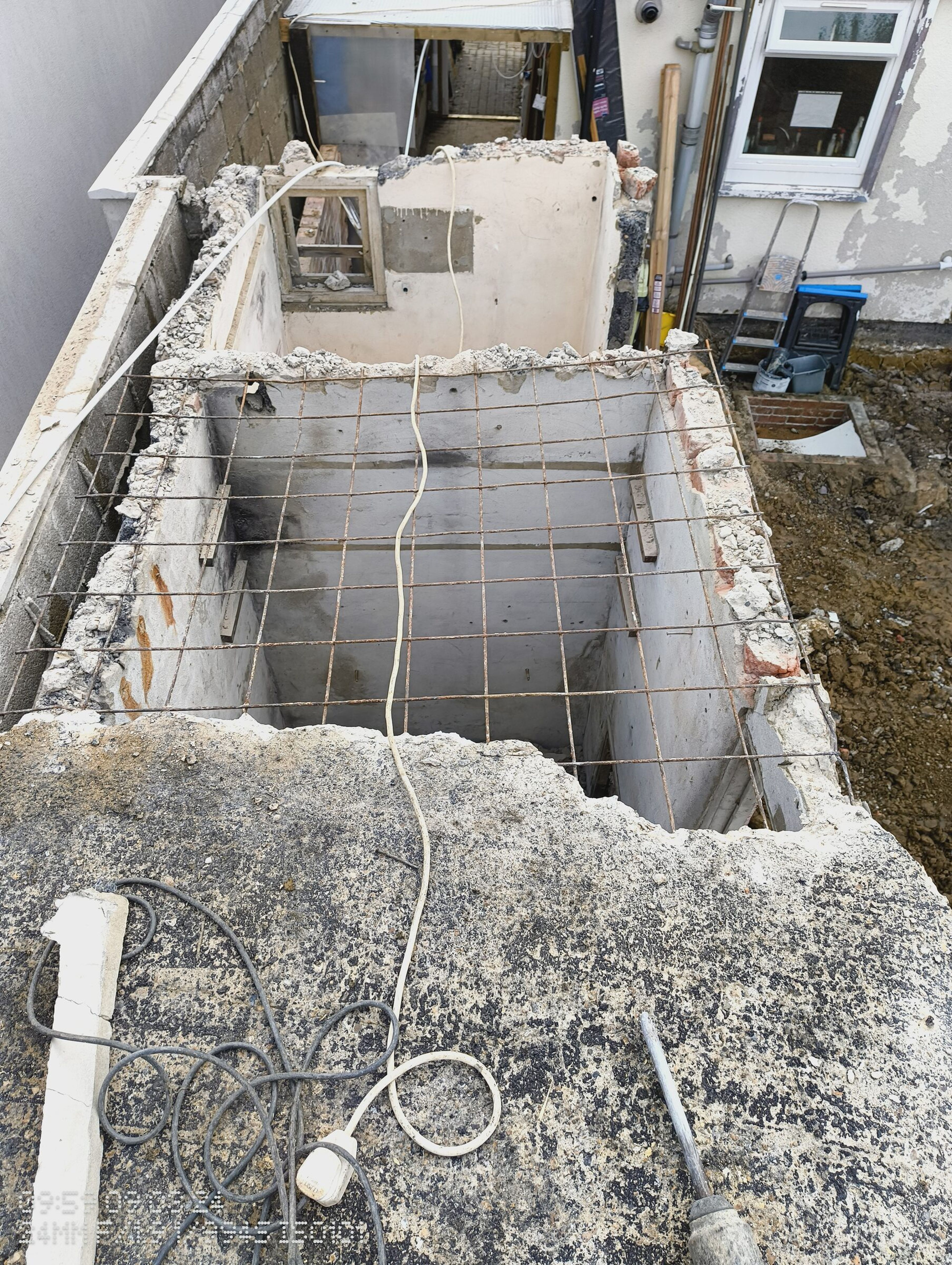 Steel mesh left spanning the opening after the concrete roof was broken out over the old extension.