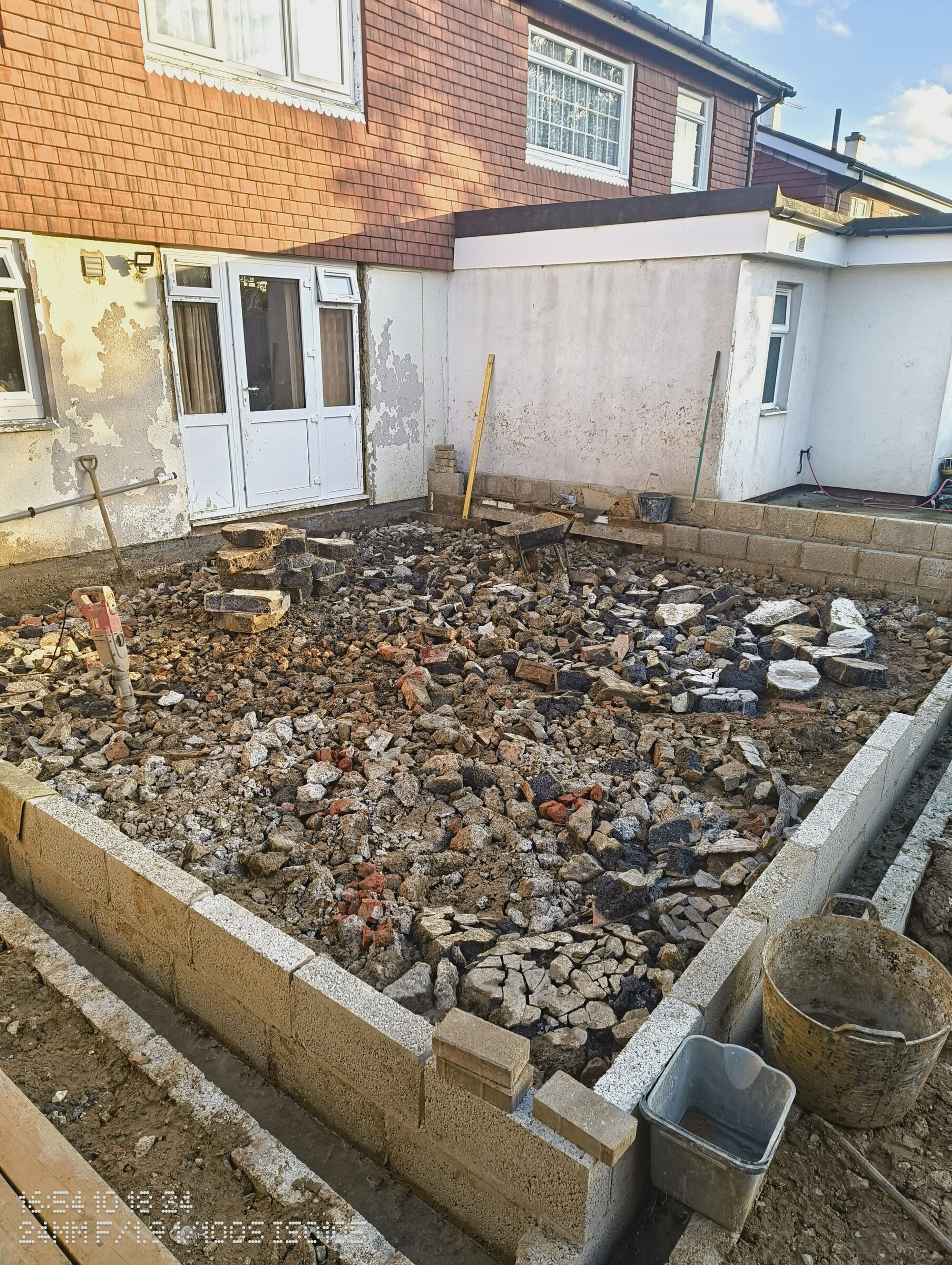 Blockwork walls enclosing a bed of hardcore against the back of the house.
