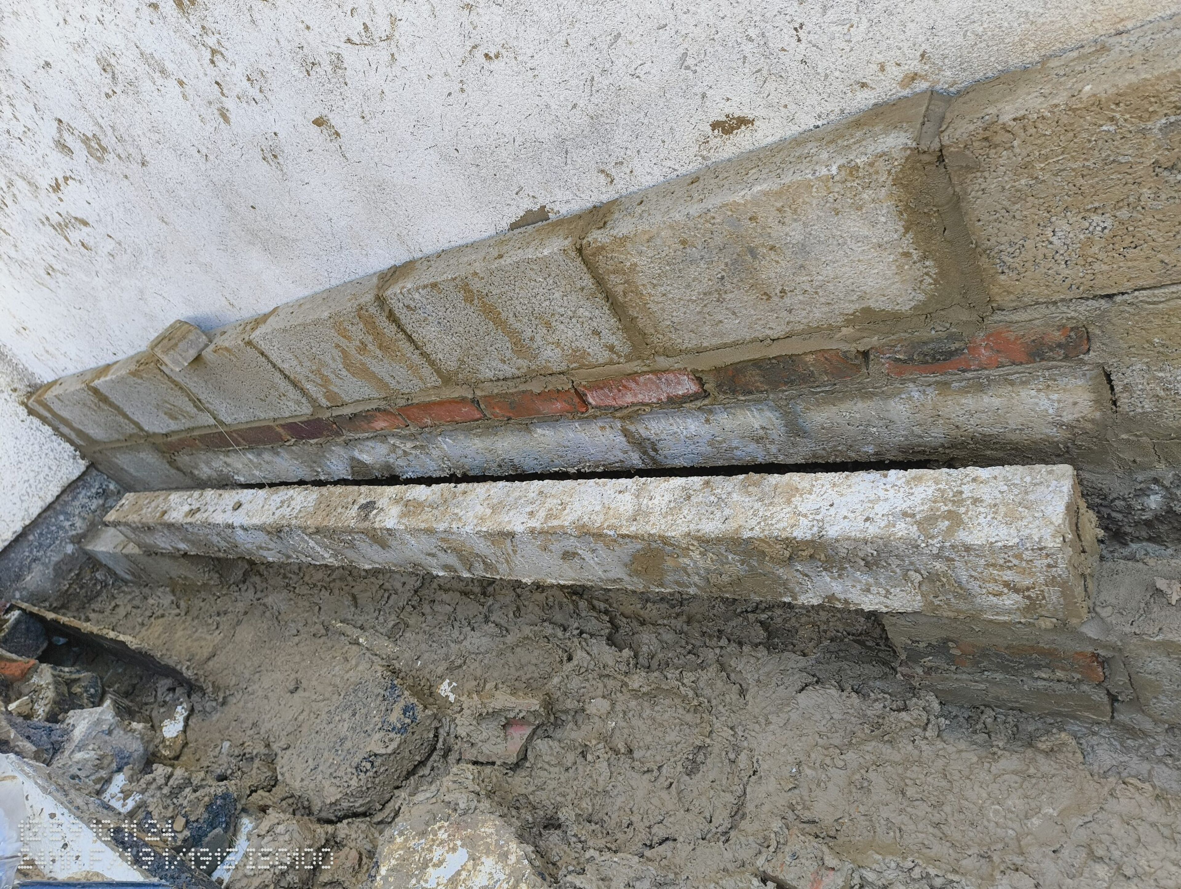 Engineering bricks and concrete blocks laid against the rendered wall of the house.