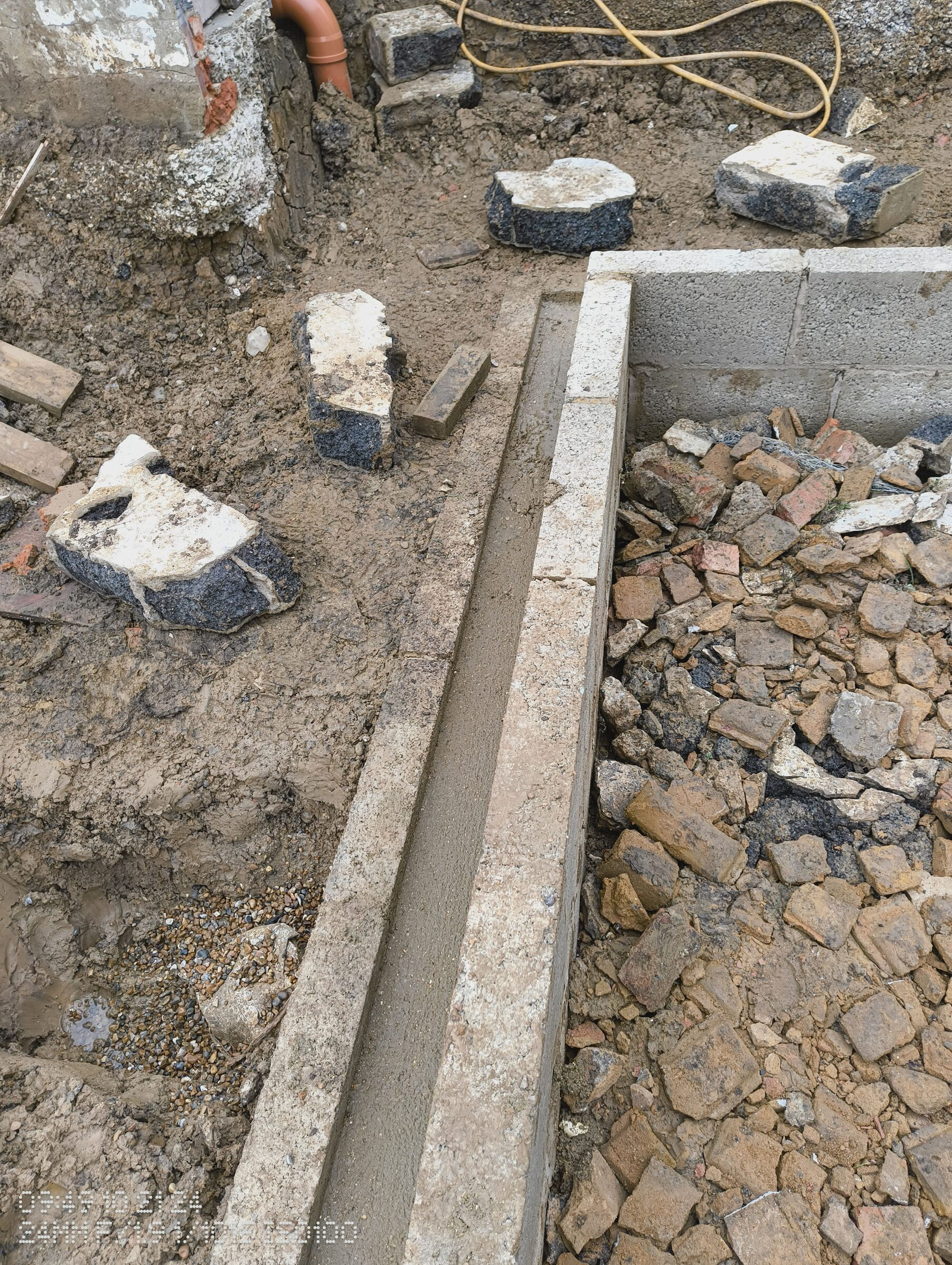 Concrete in the shuttered channel, with hardcore inside the walls and a drain at the house.