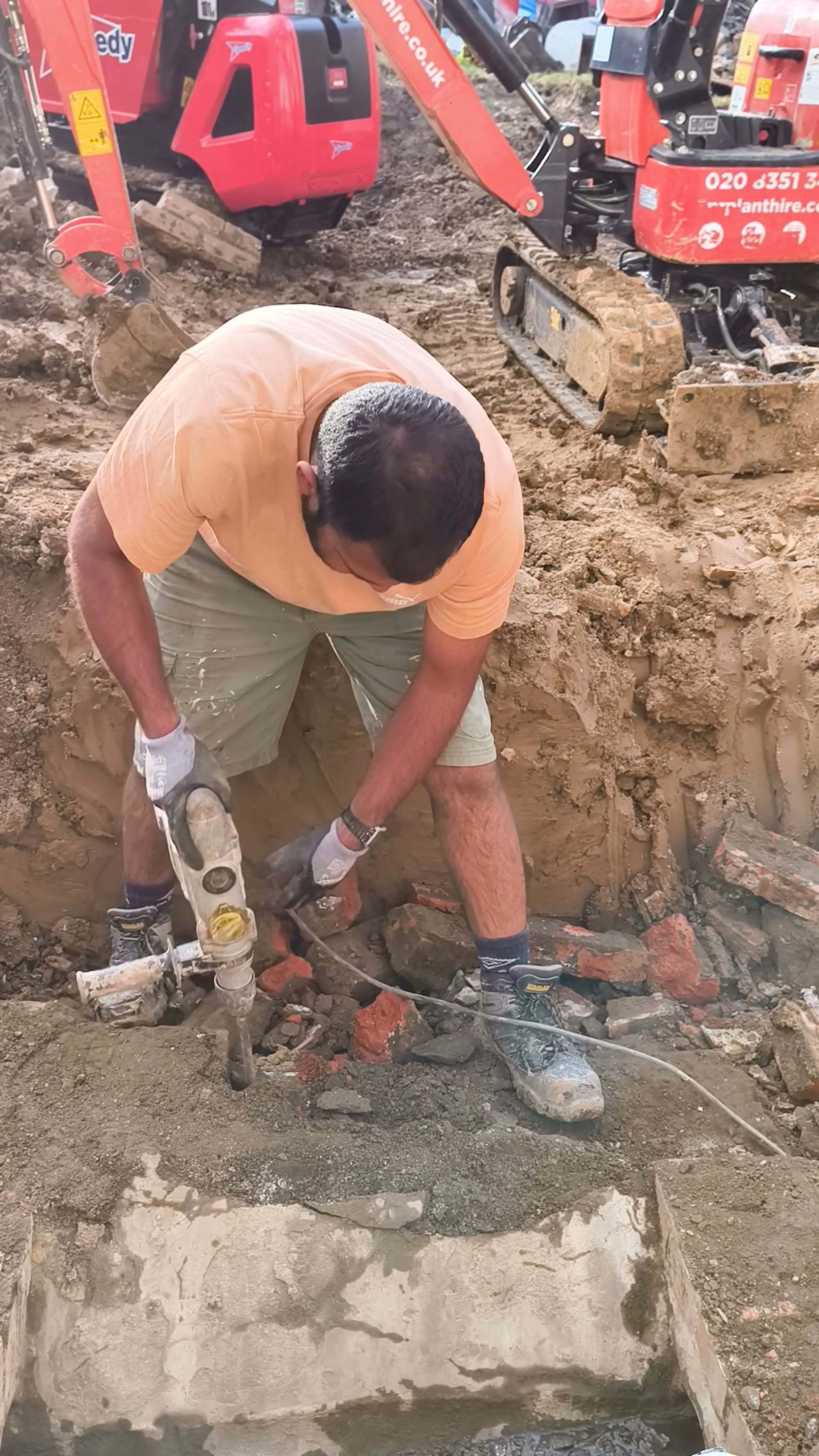 Breaking the concrete base beside a mini-digger during demolition in Chigwell