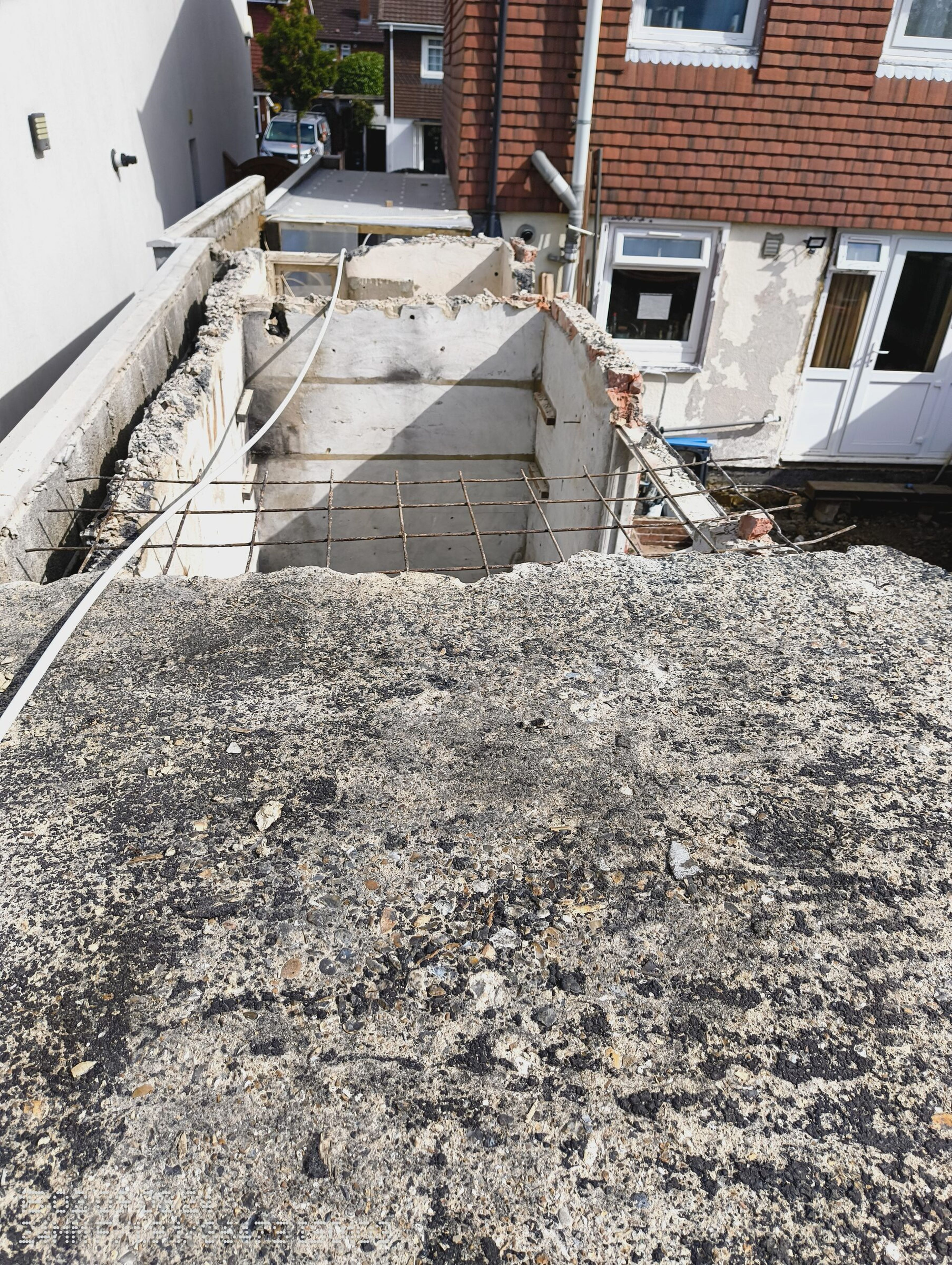 Roof largely removed from the rear extension, with mesh over the opening and the house patio doors beyond.