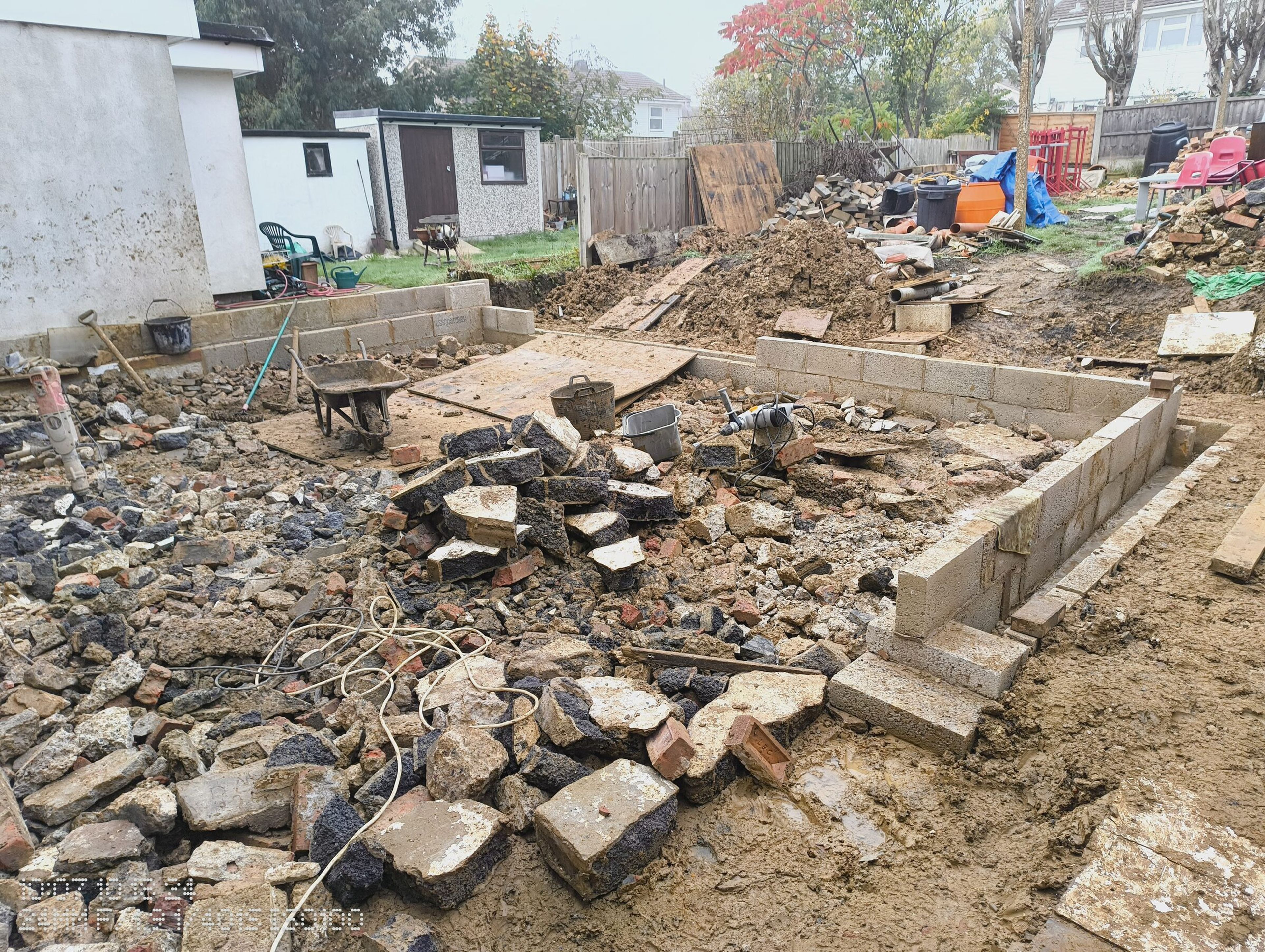 Blockwork starting along the new footprint, with rubble still filling the ground inside.