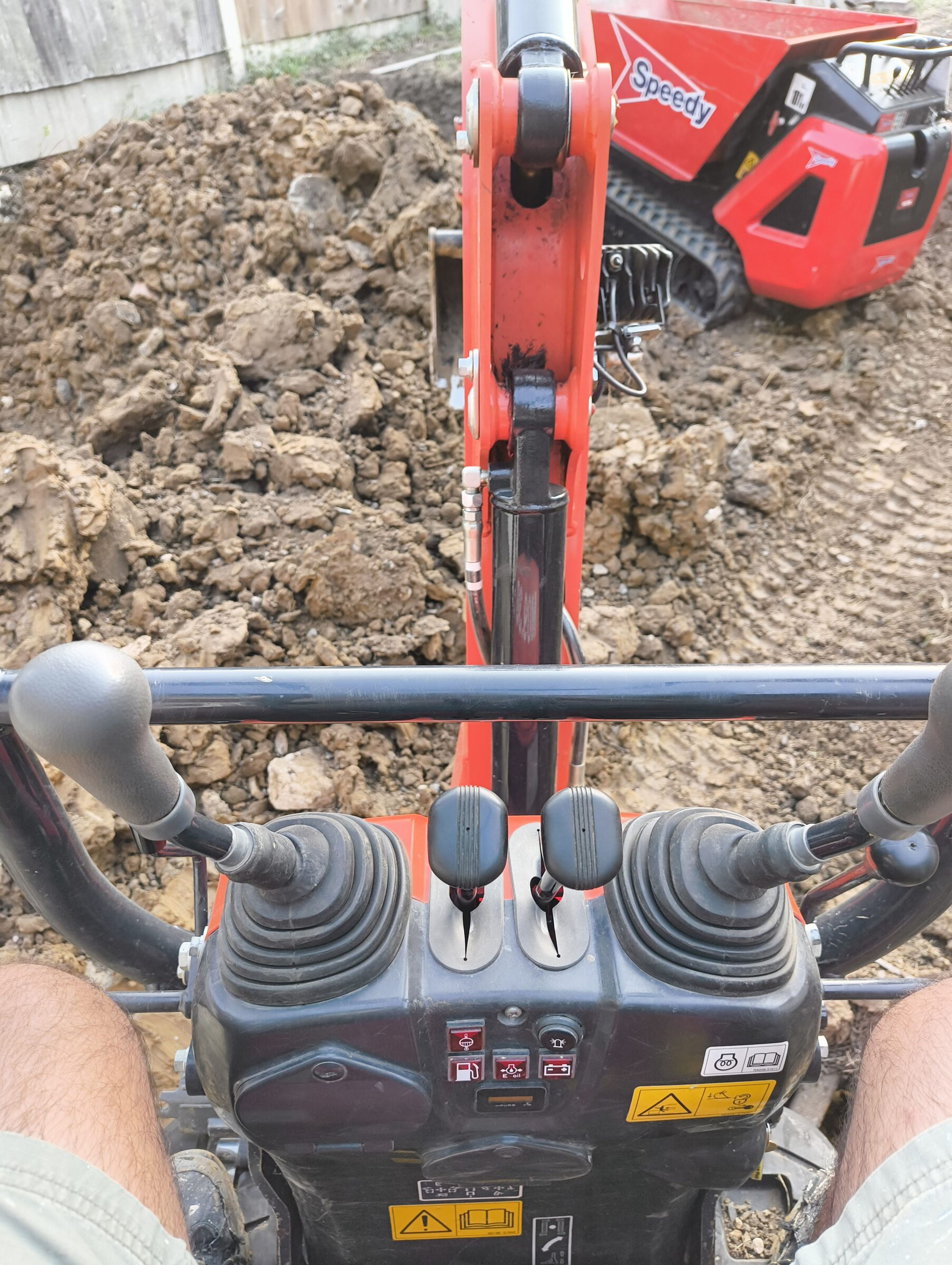 Close-up of mini digger controls in the cab during Chigwell rear extension groundworks.