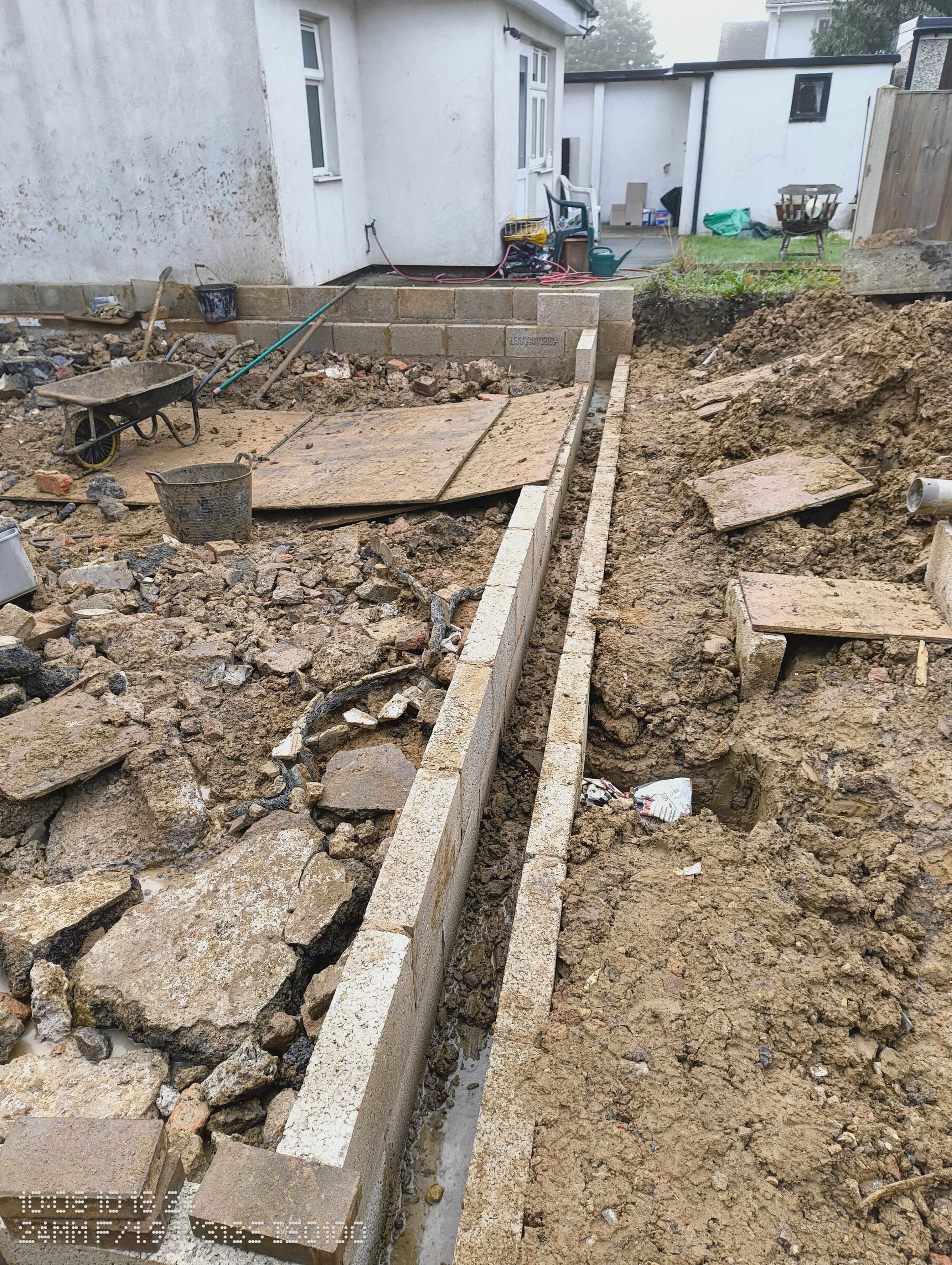 Timber shuttering set along the blockwork wall, with boards laid over the rubble inside the extension.