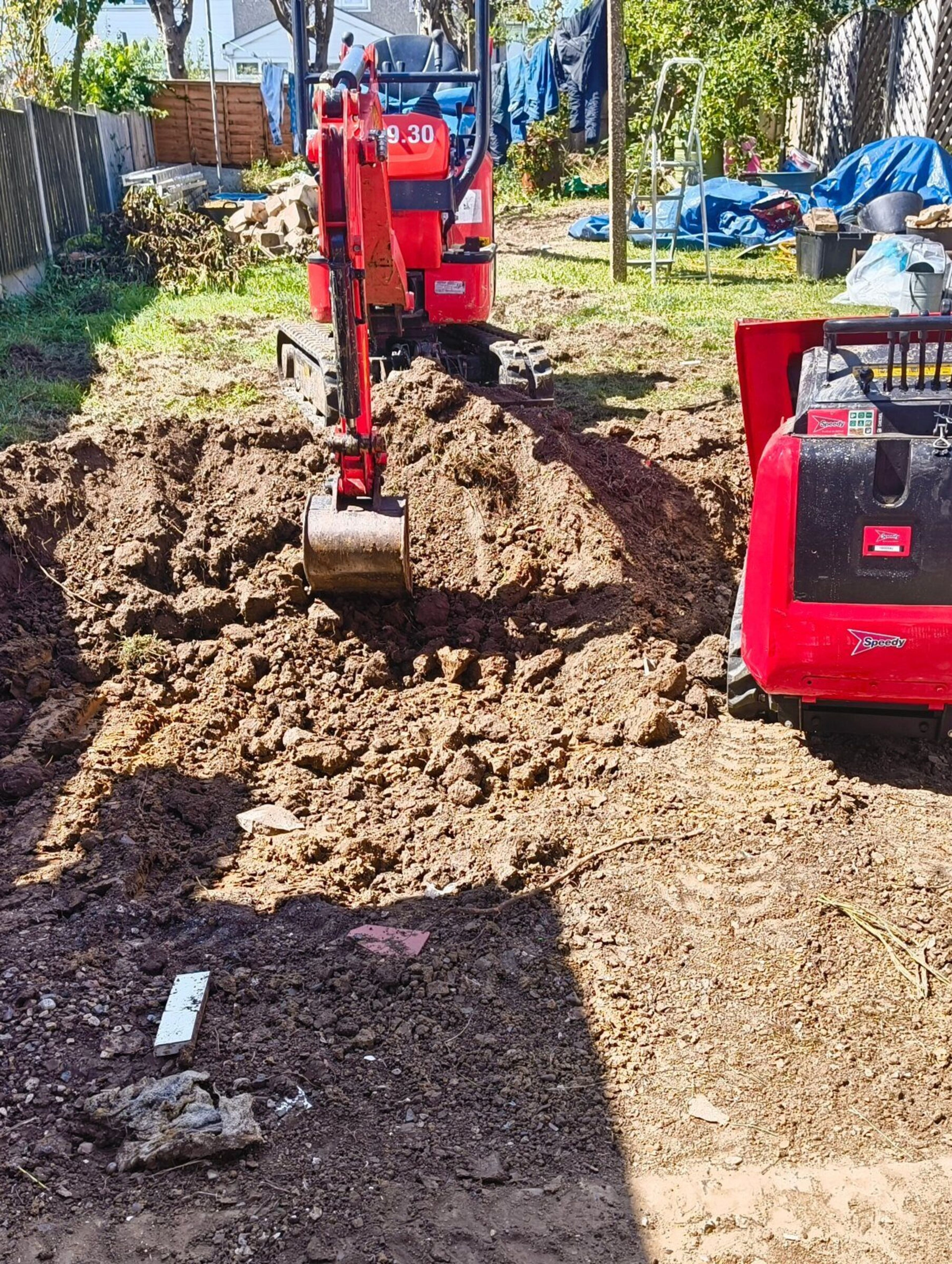 Mini digger excavating a rear garden to lower ground level for a Chigwell rear extension.