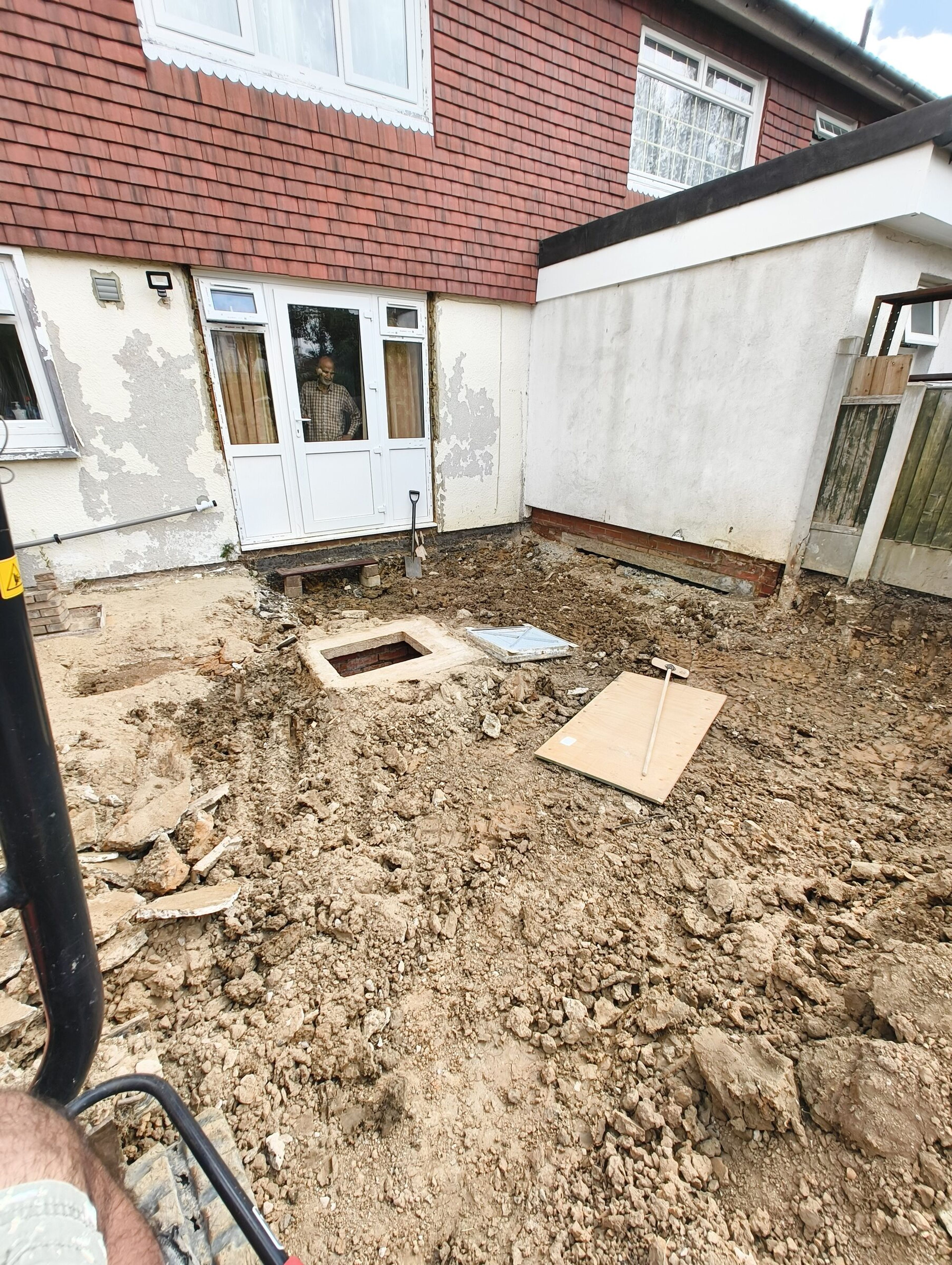 Levelled rear garden with manhole beside the house door for a Chigwell rear extension.