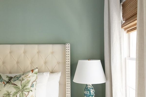 Charleston luxury vacation rental bedroom with upholstered headboard, soft green walls, natural light, and designer styling by Respite & Revelry Co.