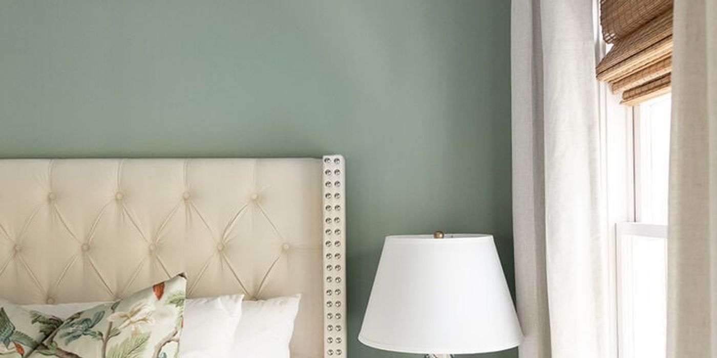 Charleston luxury vacation rental bedroom with upholstered headboard, soft green walls, natural light, and designer styling by Respite & Revelry Co.