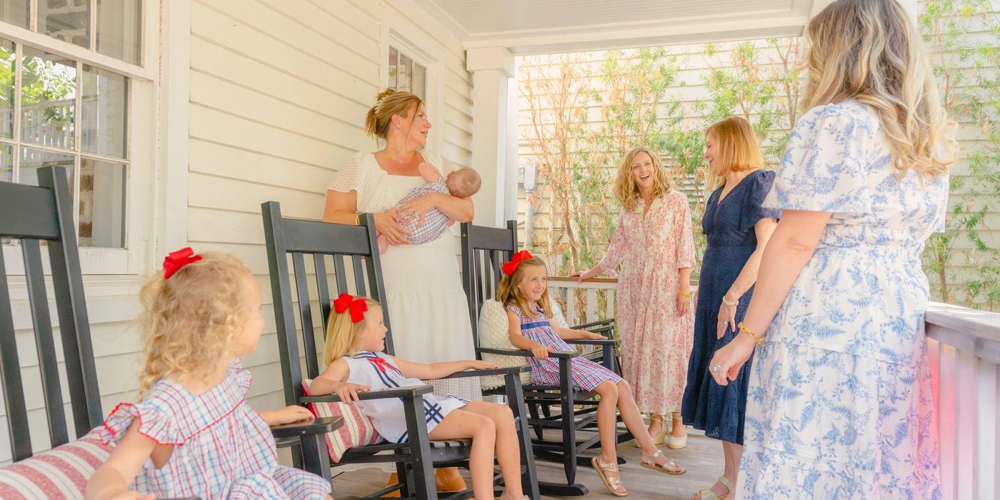 Group of women and children gathering on the front porch of a Charleston SC vacation rental with rocking chairs