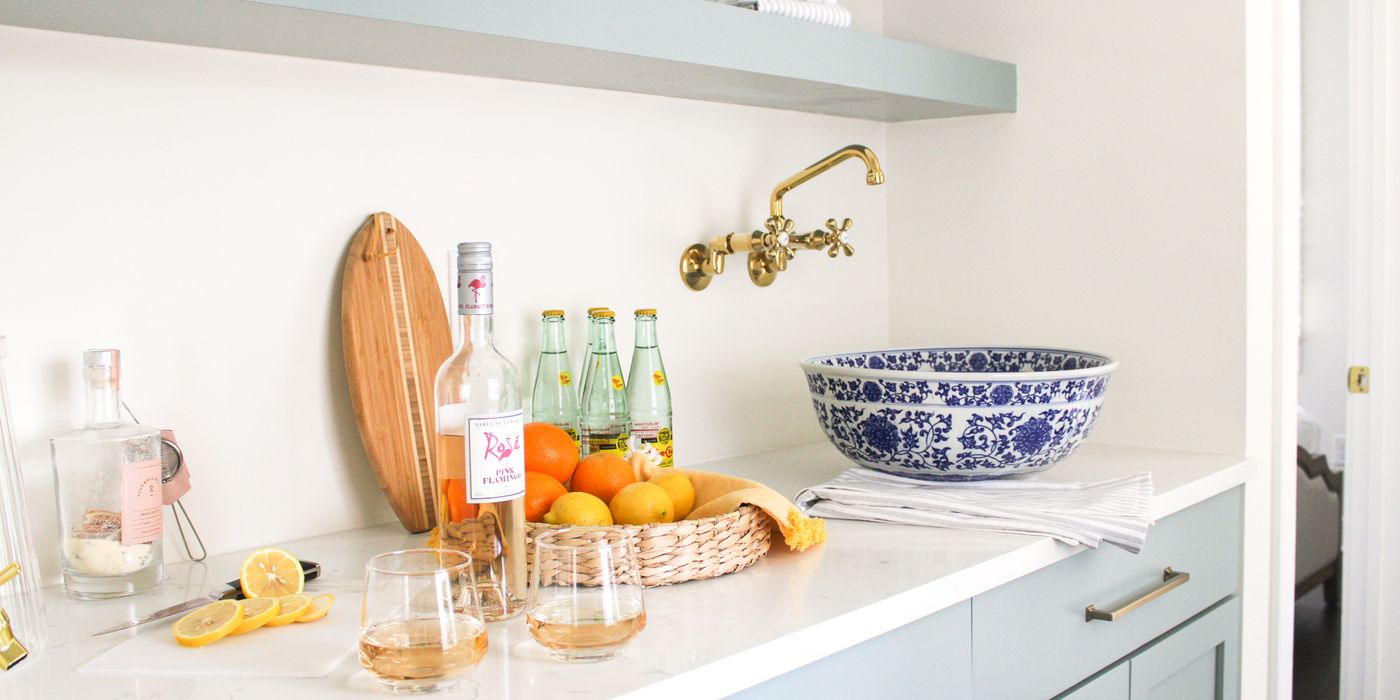 Luxury Charleston vacation rental wet bar with brass faucet, marble countertop, citrus styling, and curated blue and white decor by Respite & Revelry Co.