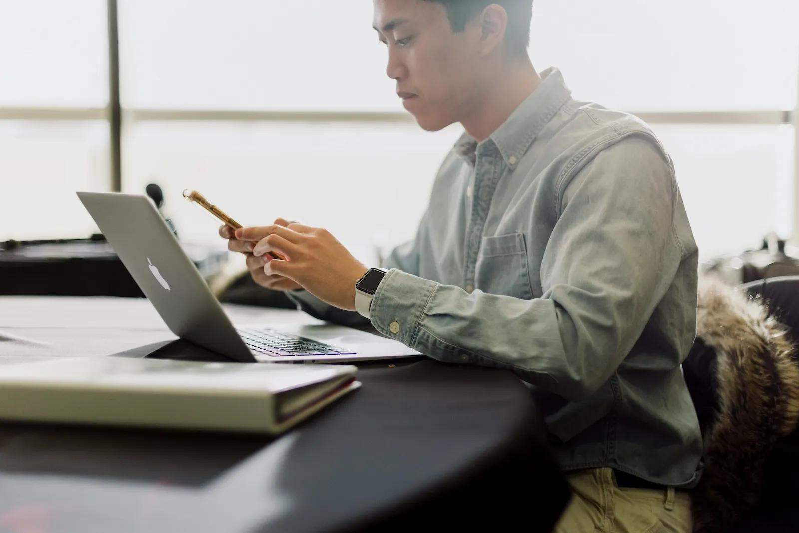 Business professional reviewing information across laptop and phone, illustrating registered agent compliance risks and missed legal notices