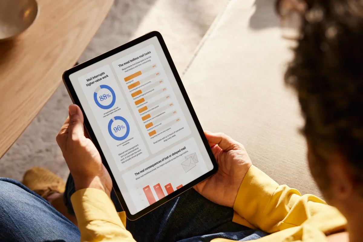 A person in a yellow sweater holds a tablet displaying Stable's Business Mail Management Research infographic, showing data on how mail interrupts higher-value work — including statistics that 88% of respondents and 96% of mid-size and enterprise companies