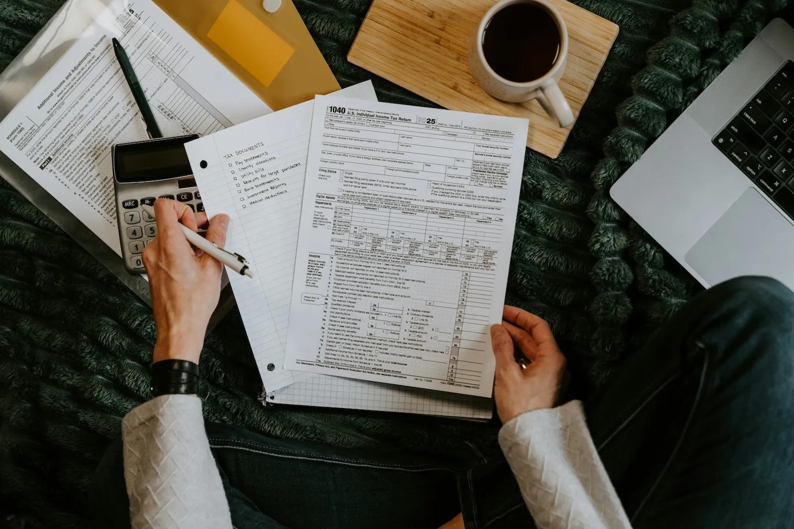 Overhead view of small business tax forms, calculator, and paperwork on a desk during tax preparation