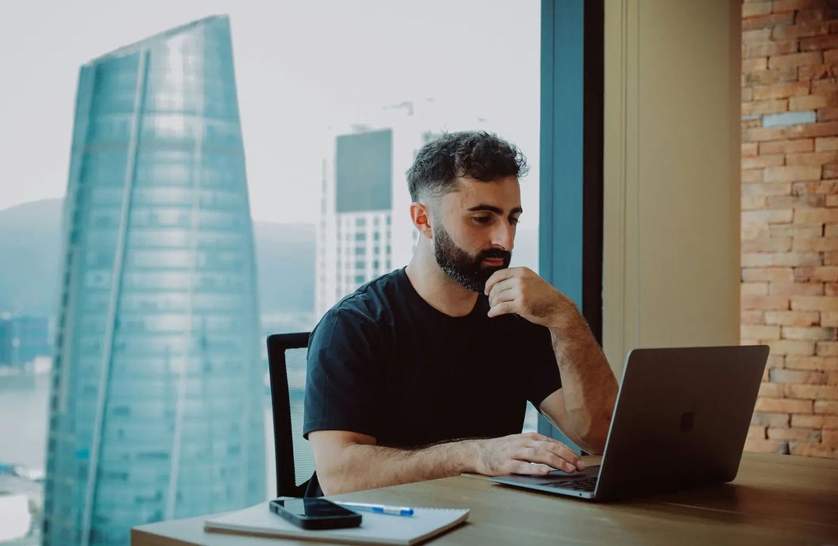 Startup founder working on a laptop in a transitional space, representing the challenge of using a personal address for a growing business