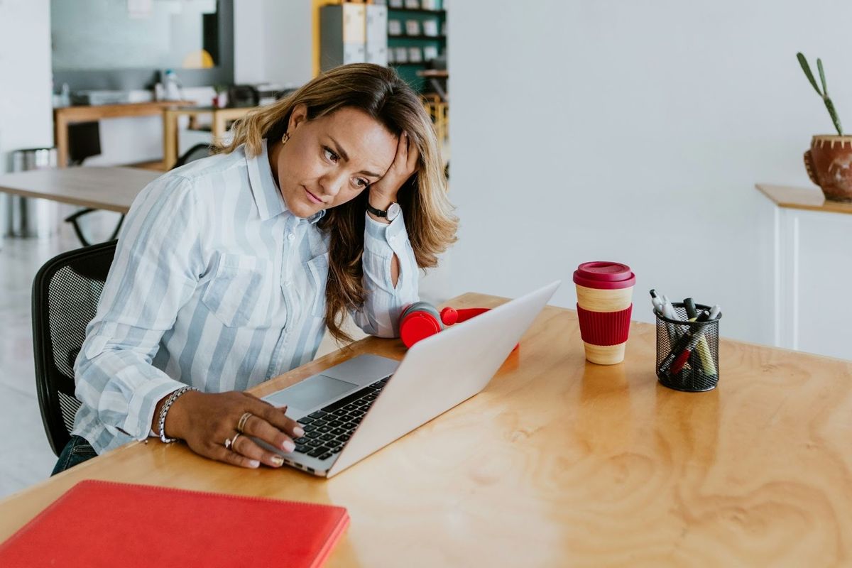 Professional looking frustrated at her laptop while managing repetitive administrative tasks