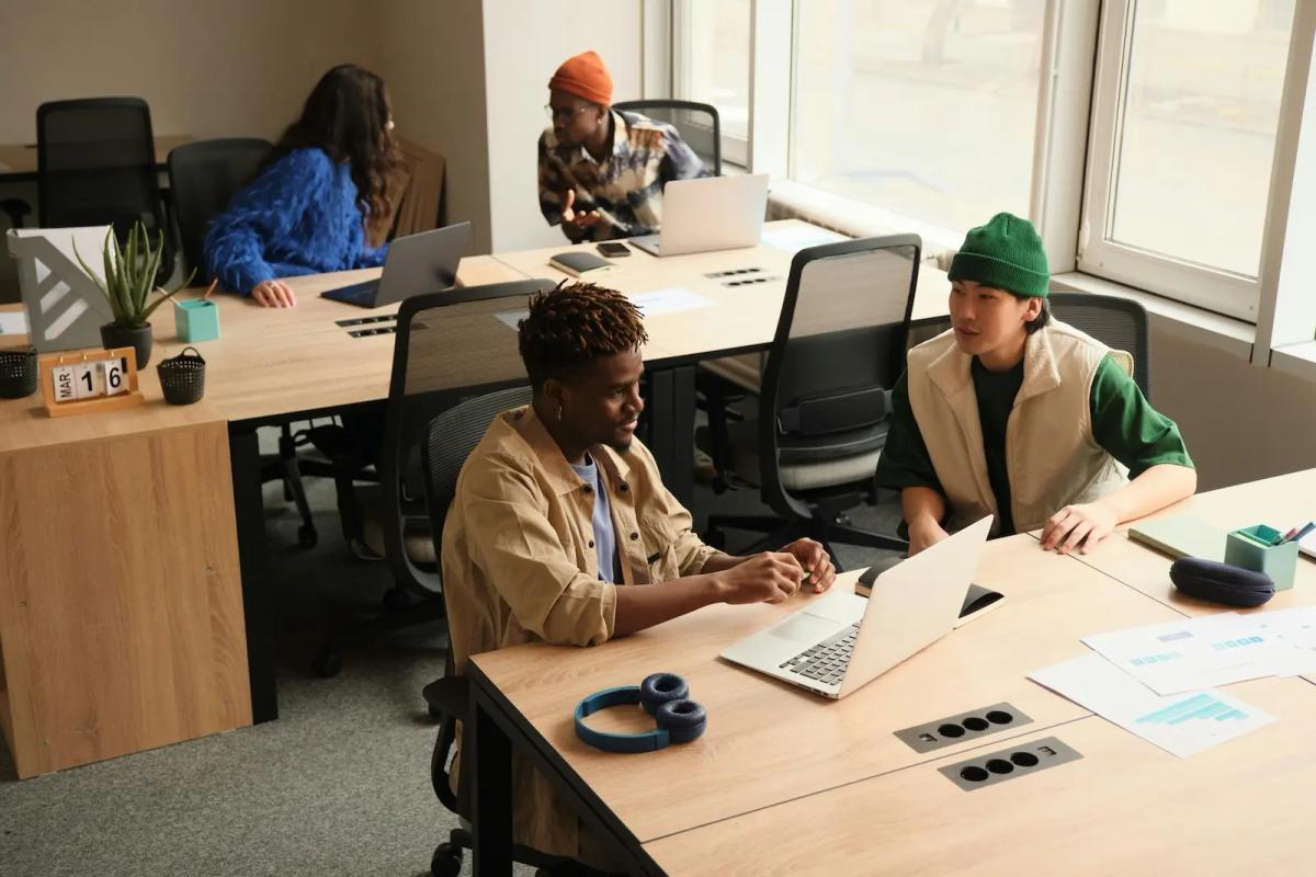 Small business team collaborating at laptops with printed documents on the desk, illustrating how teams manage mail-driven workflows
