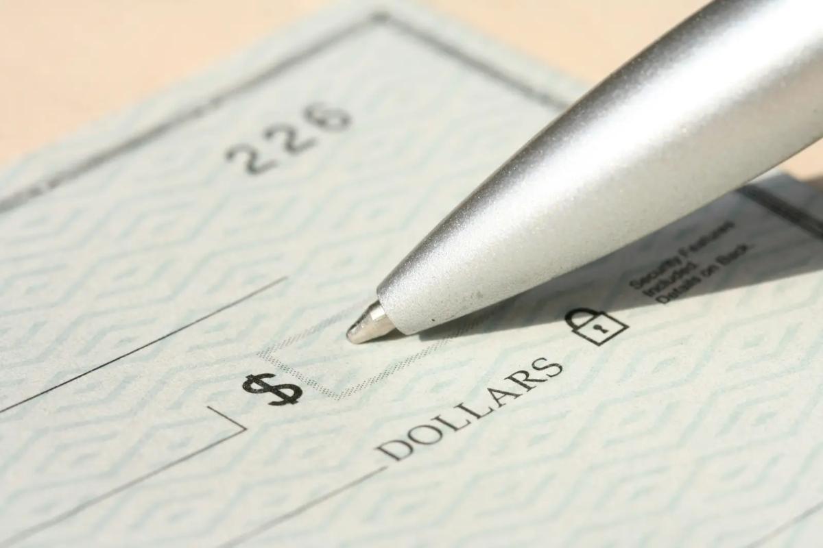 Close-up of a paper check being filled out, representing manual payment processing that electronic check deposits replace