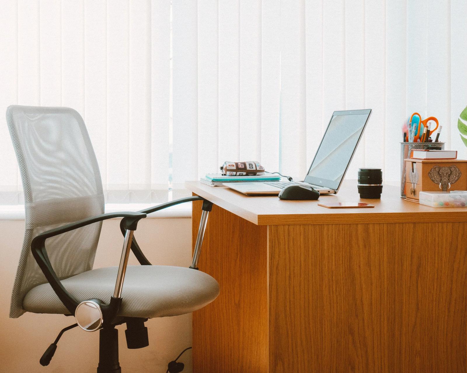 A home office desk with a laptop and office chair, representing a small business owner using a virtual address for their LLC