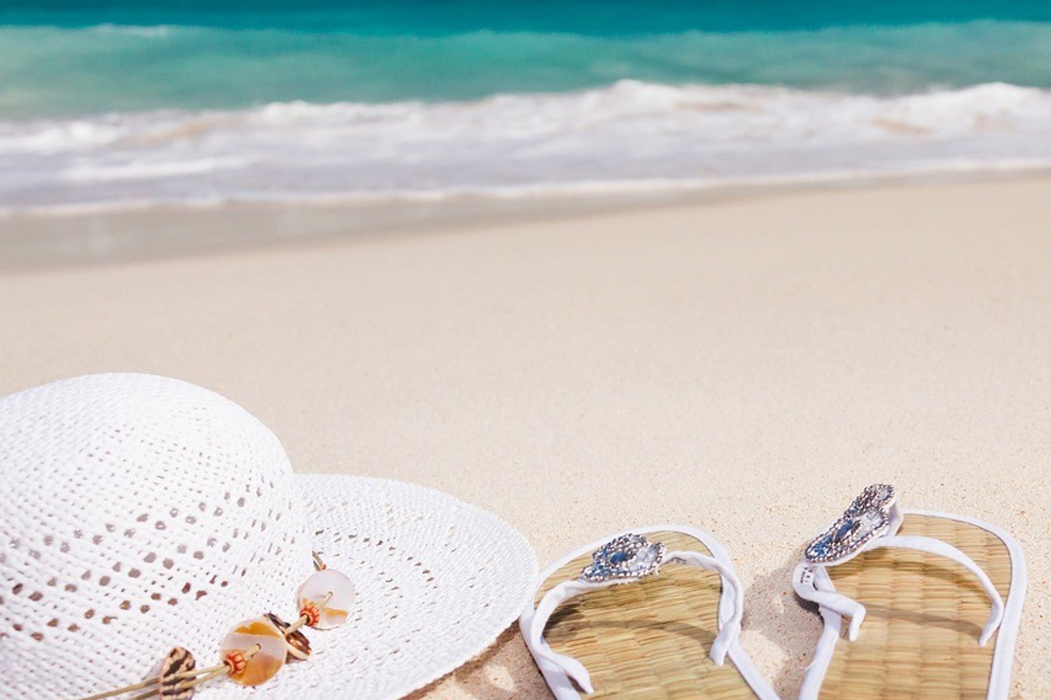Solhatt på sandaler på en vit strand