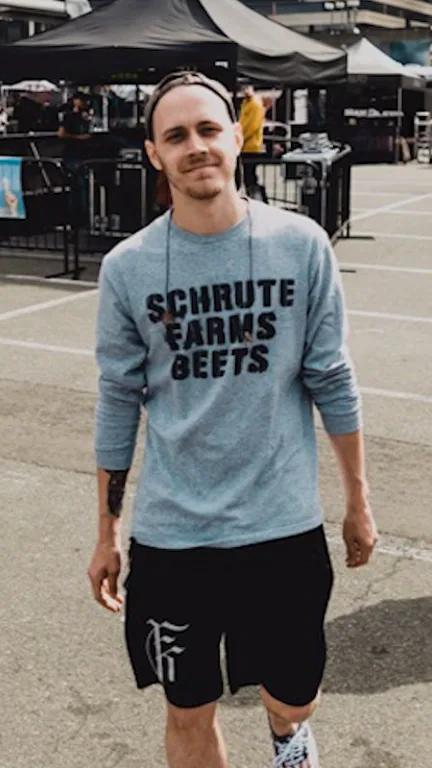 Cameron Copper standing outdoors at a music festival in a gray sweatshirt.