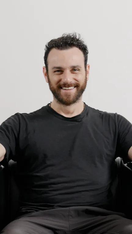 Zack smiling while seated in a black T-shirt.