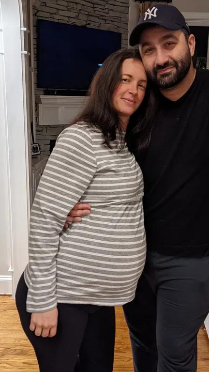Sarah Levit in a striped top standing with her partner indoors.