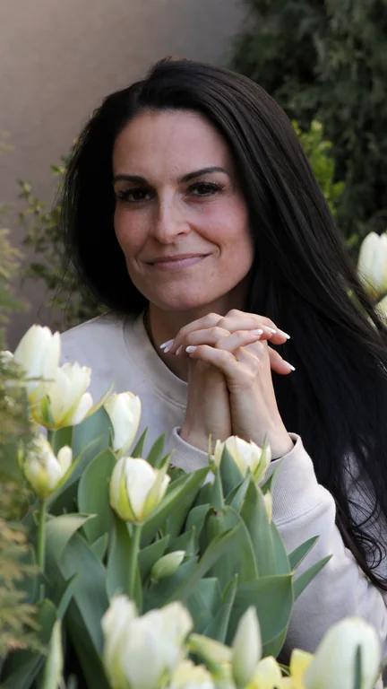 Melissa Johnson with her hands clasped beneath her chin, surrounded by white tulips.