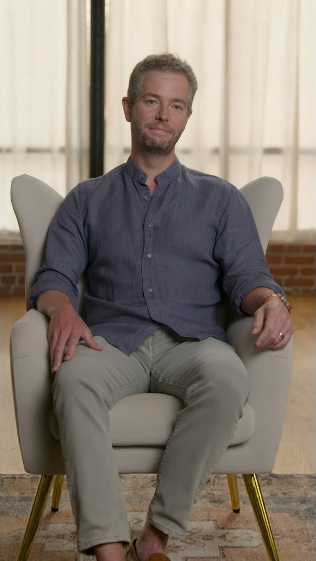 Ian Sanders sitting in a chair smiling at the camera.