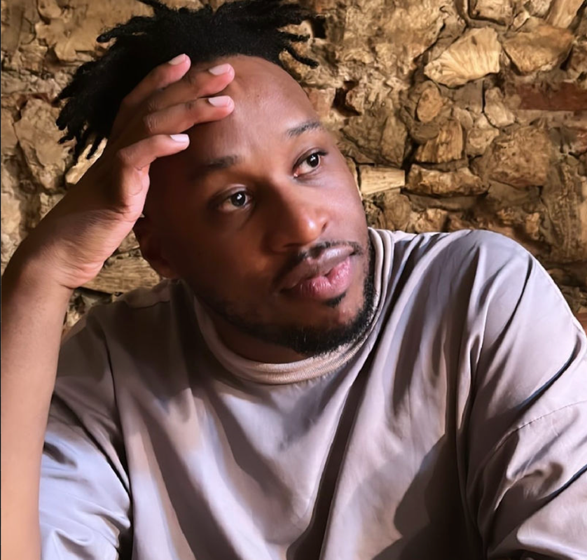 a man with dreadlocks holds his hand to his forehead