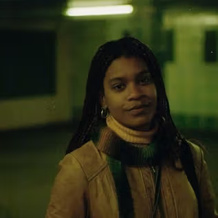 a woman wearing a scarf and a jacket is standing in a dark room
