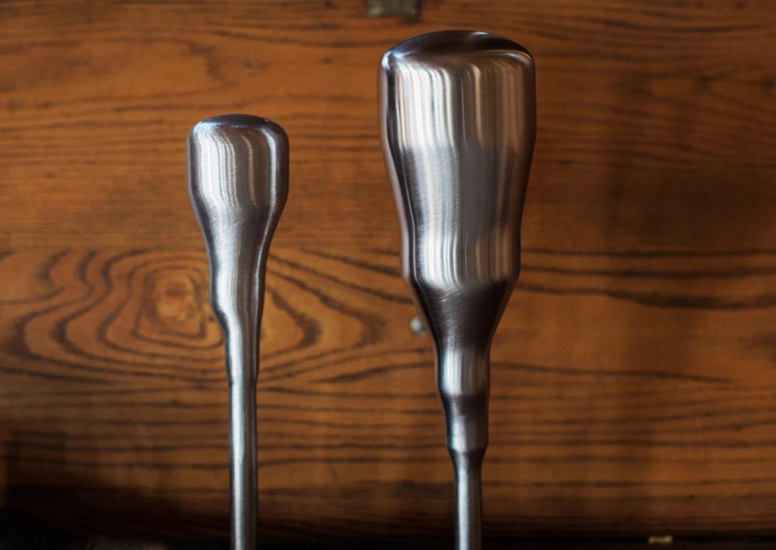 two stainless steel screwdrivers are sitting on a wooden table .